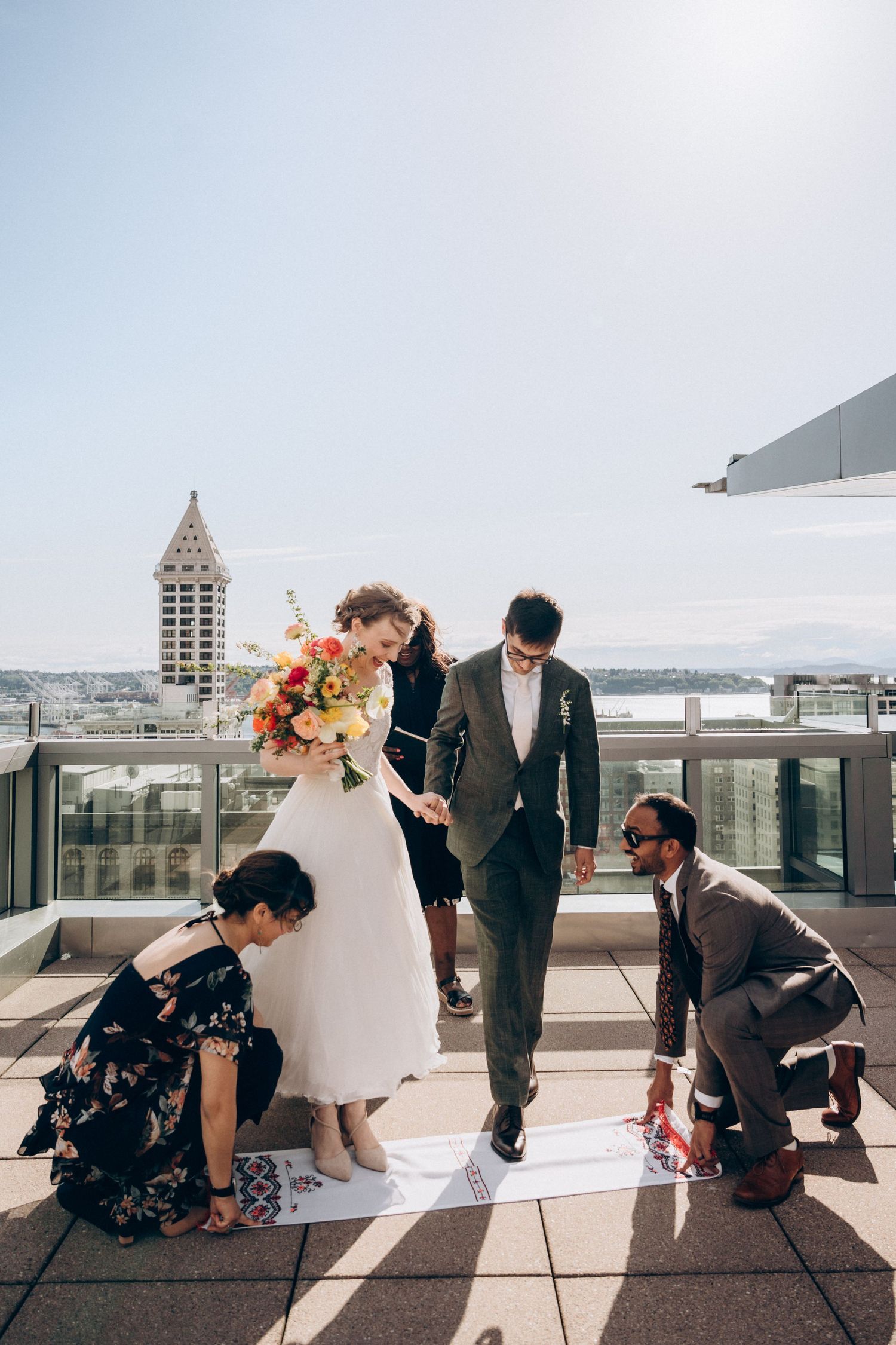 Small wedding ceremony taking place on a rooftop terrace with Seattle's Smith Tower visible in the background.