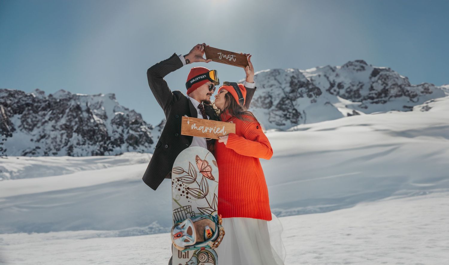 Couple eloping in the snowy mountains of PNW, joyfully holding a 'just married' sign