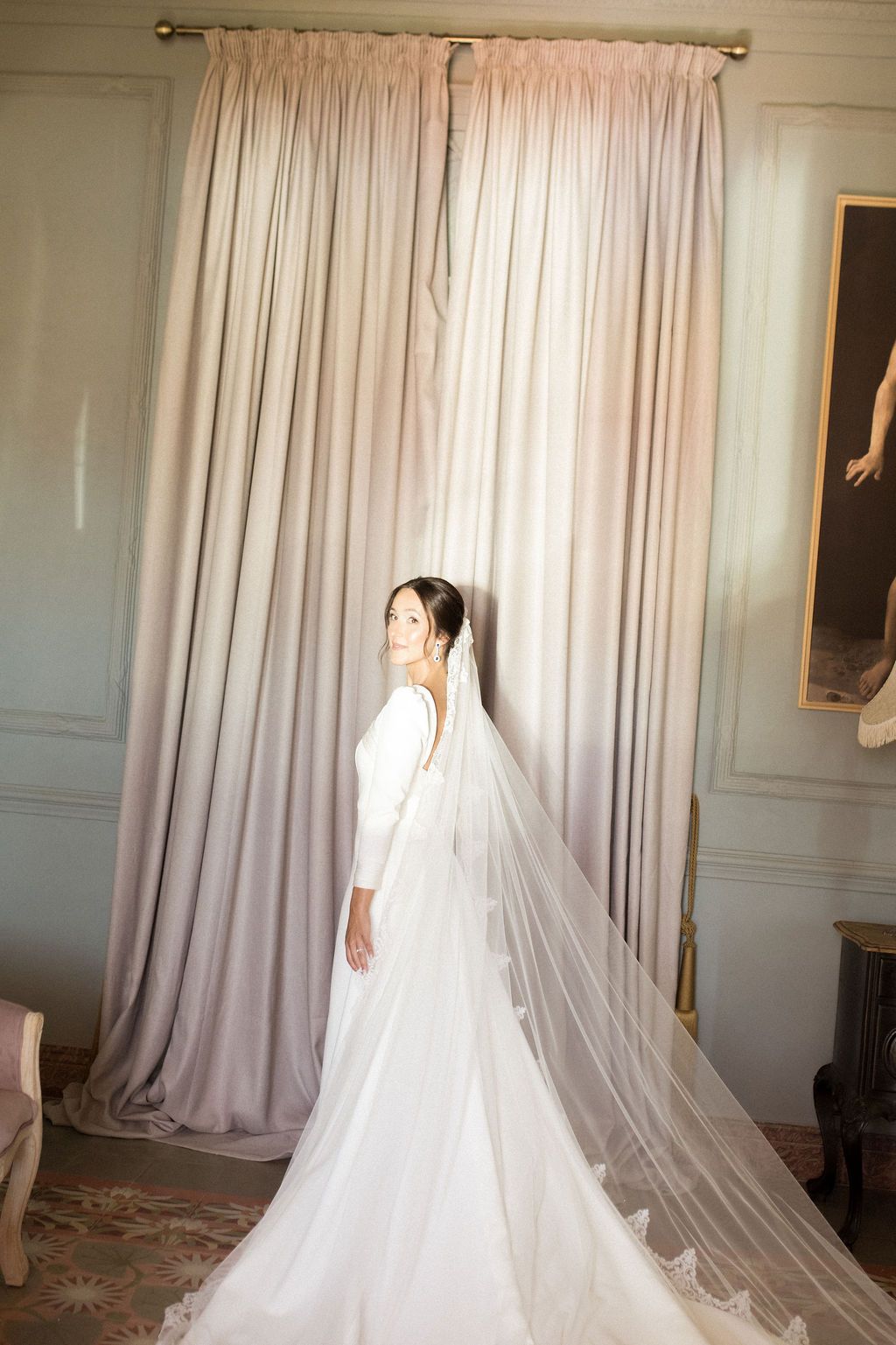 A flowing white wedding dress and veil captured in elegant bridal preparation shots.
