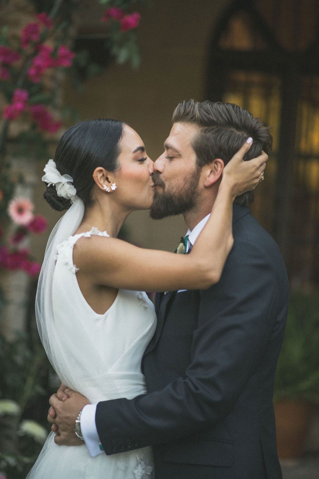 Romantic wedding kiss captured during an outdoor ceremony with natural lighting.