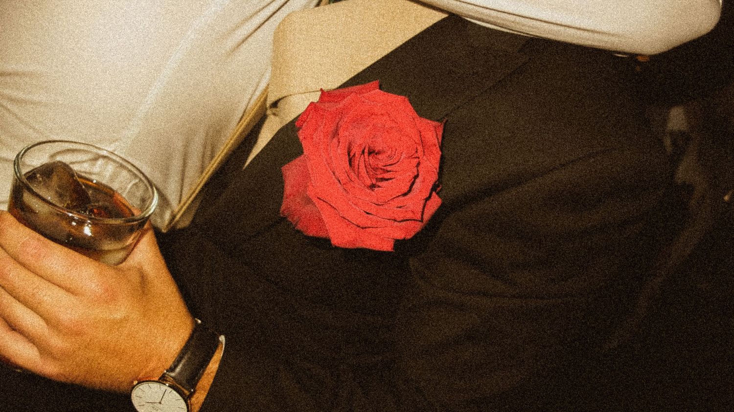Close-up detail of formal attire with a red rose accent.