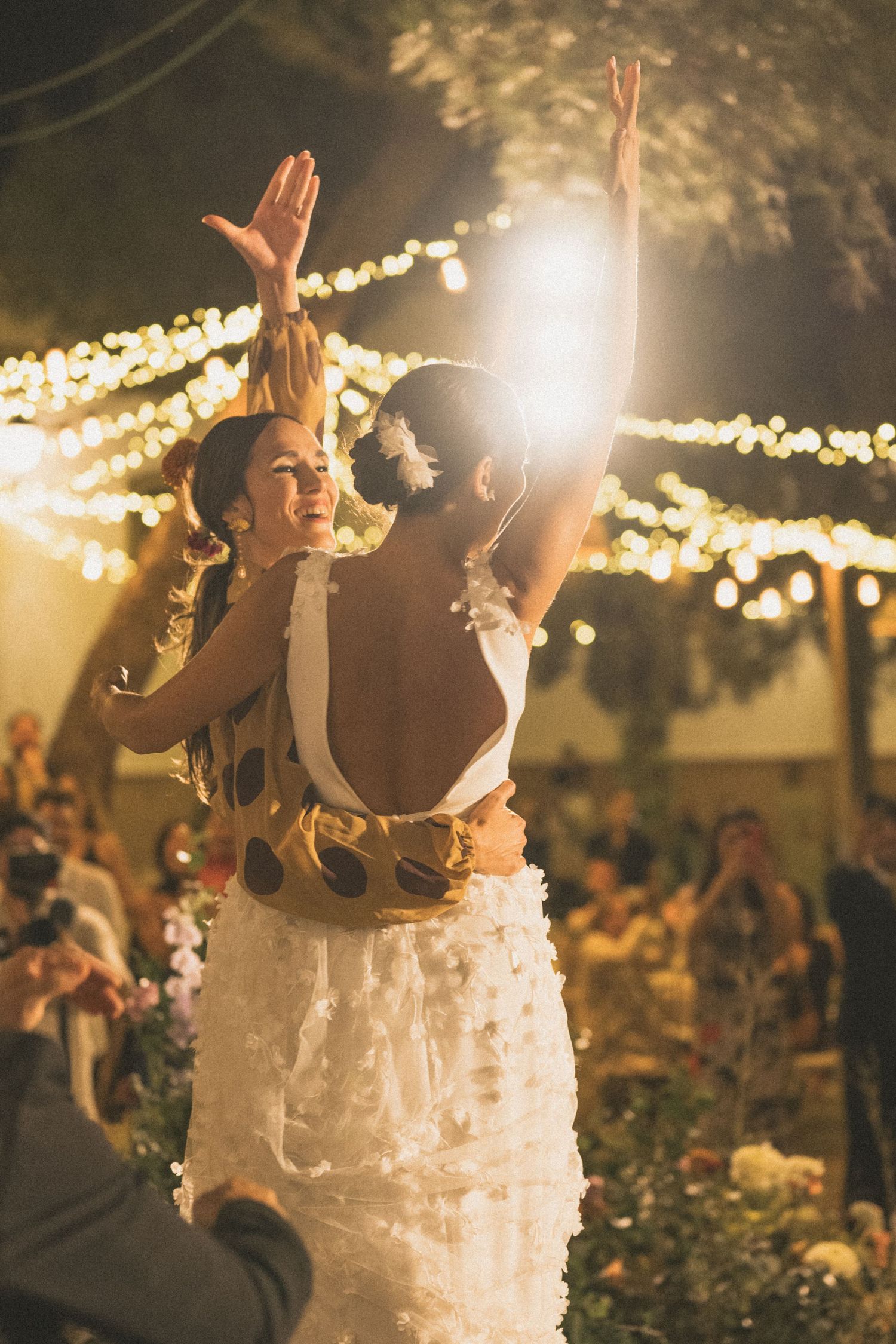 Joyful celebration moment under twinkling lights at an outdoor wedding reception.