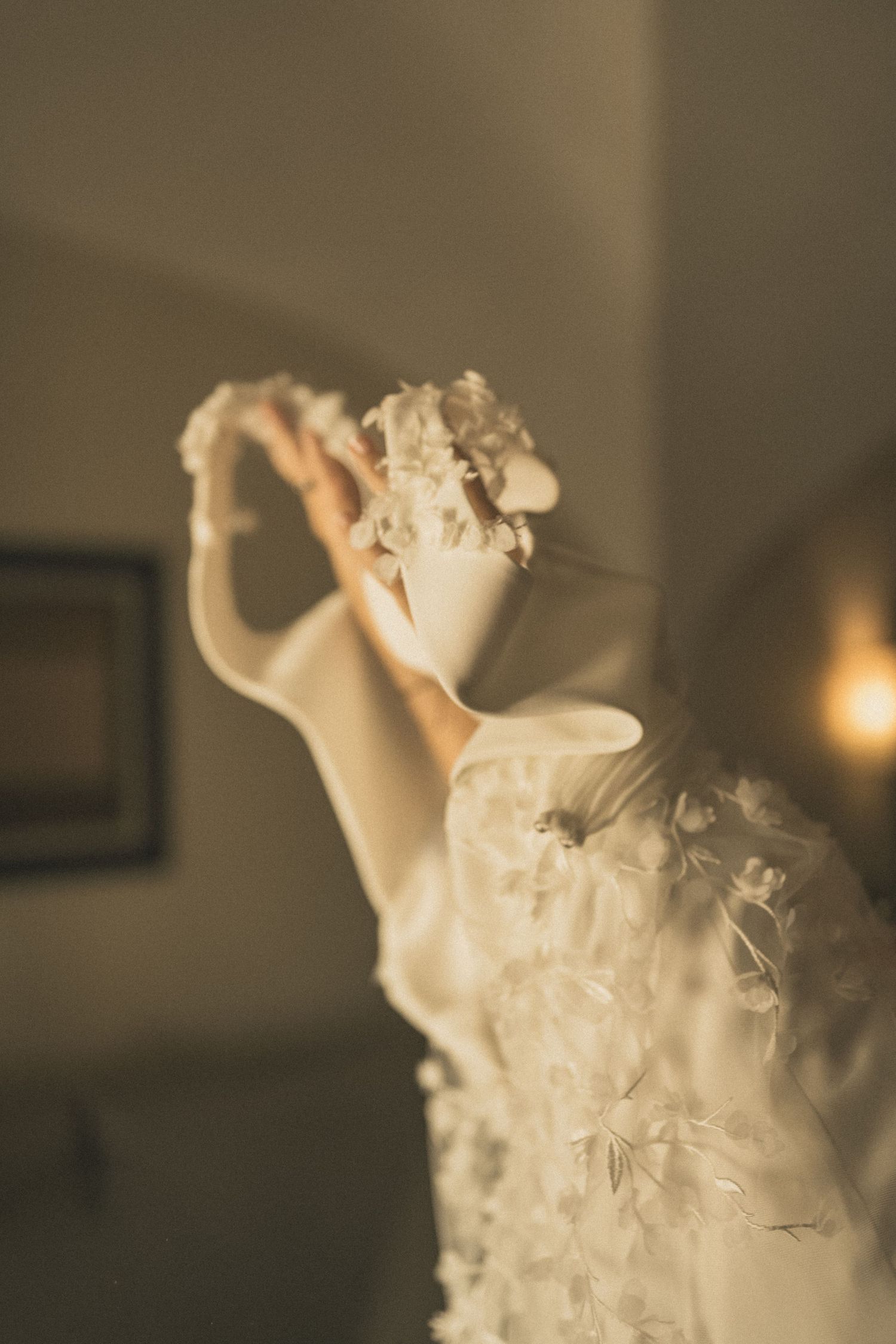 A flowing white wedding dress photographed in elegant motion with soft focus.