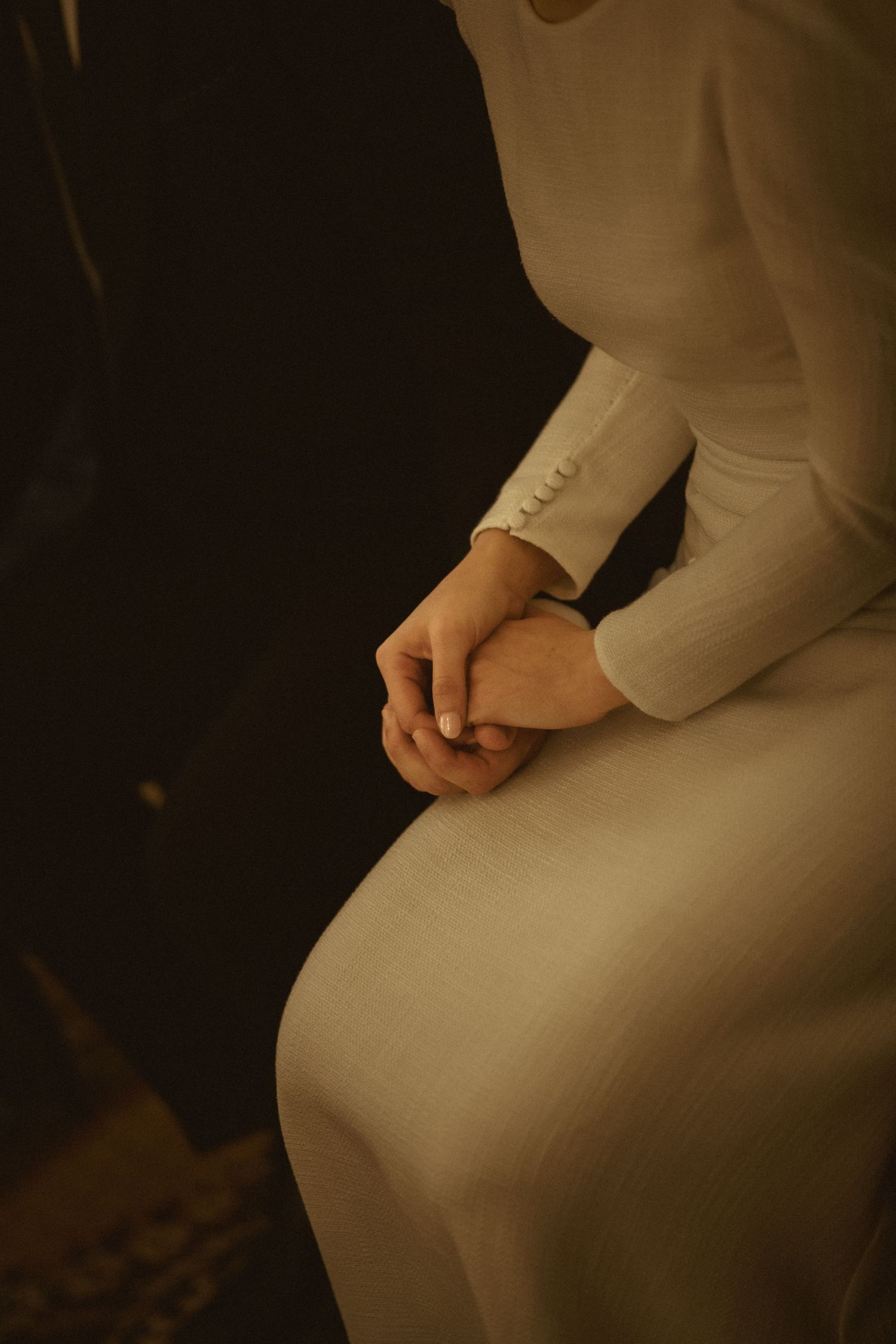 Close-up detail of white wedding dress fabric in dim lighting.