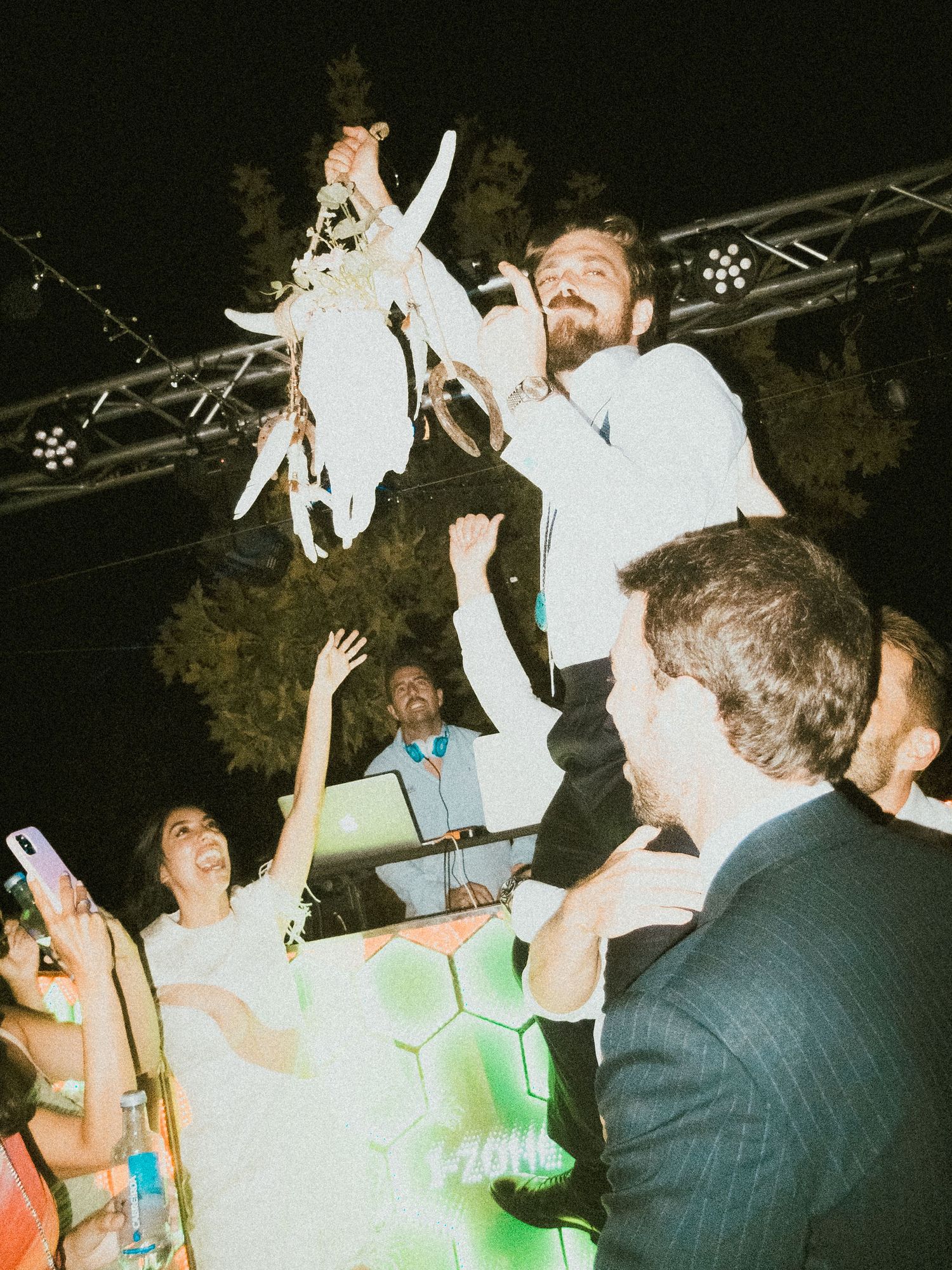 Energetic crowd dancing and celebrating at a nighttime party with stage lighting.