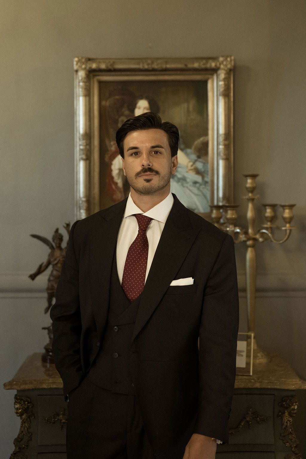 A formal portrait of a groom in a classic black suit and red tie.