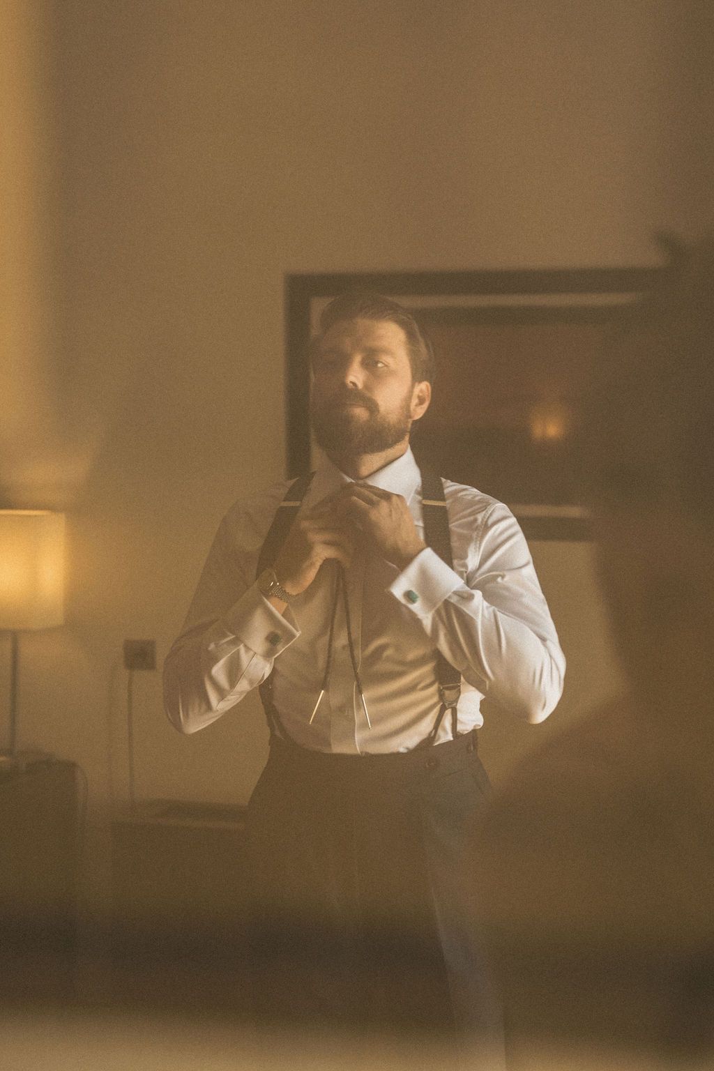 Silhouette of someone adjusting their tie in warm ambient lighting.