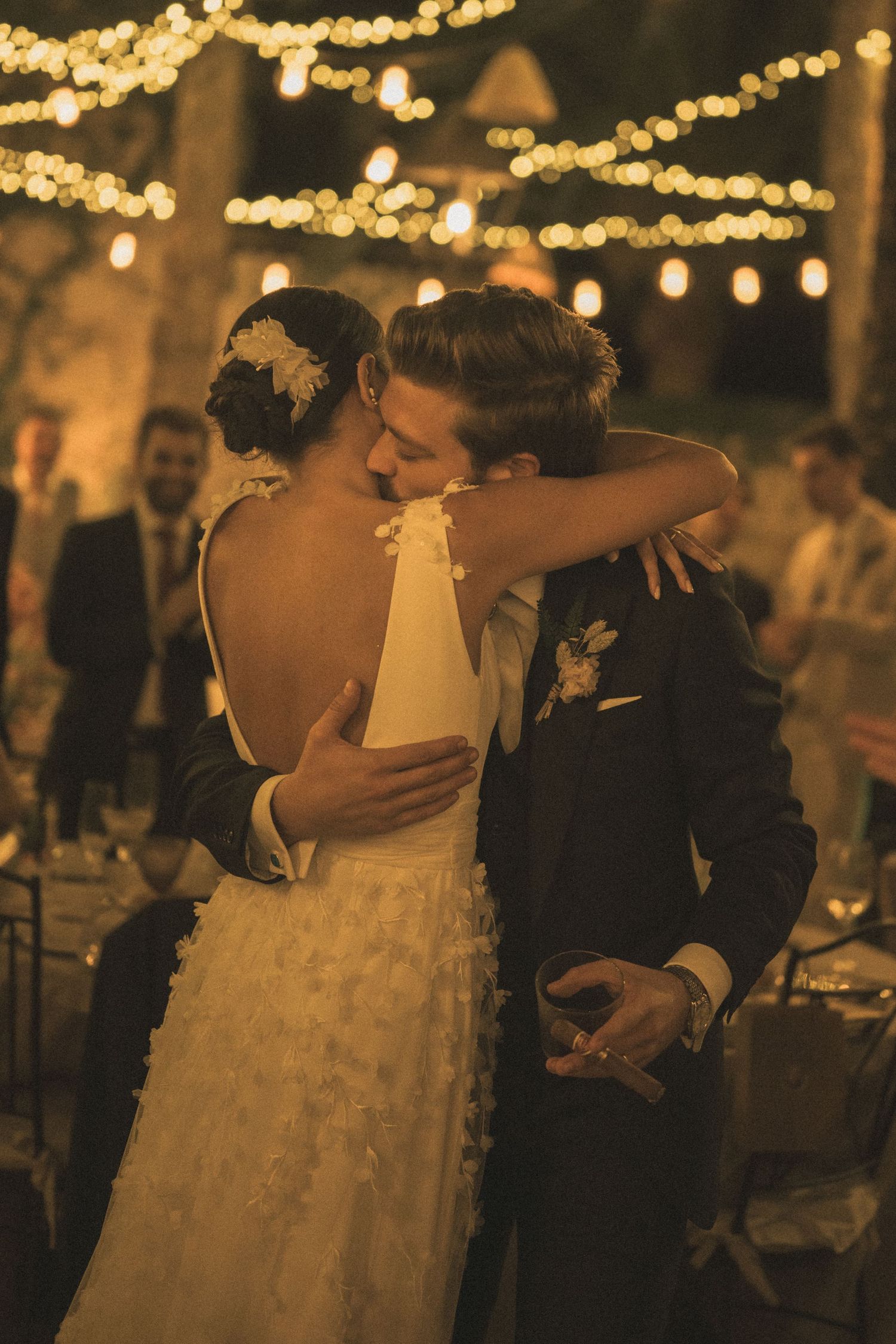 Couple sharing an intimate dance moment under glowing string lights at reception.