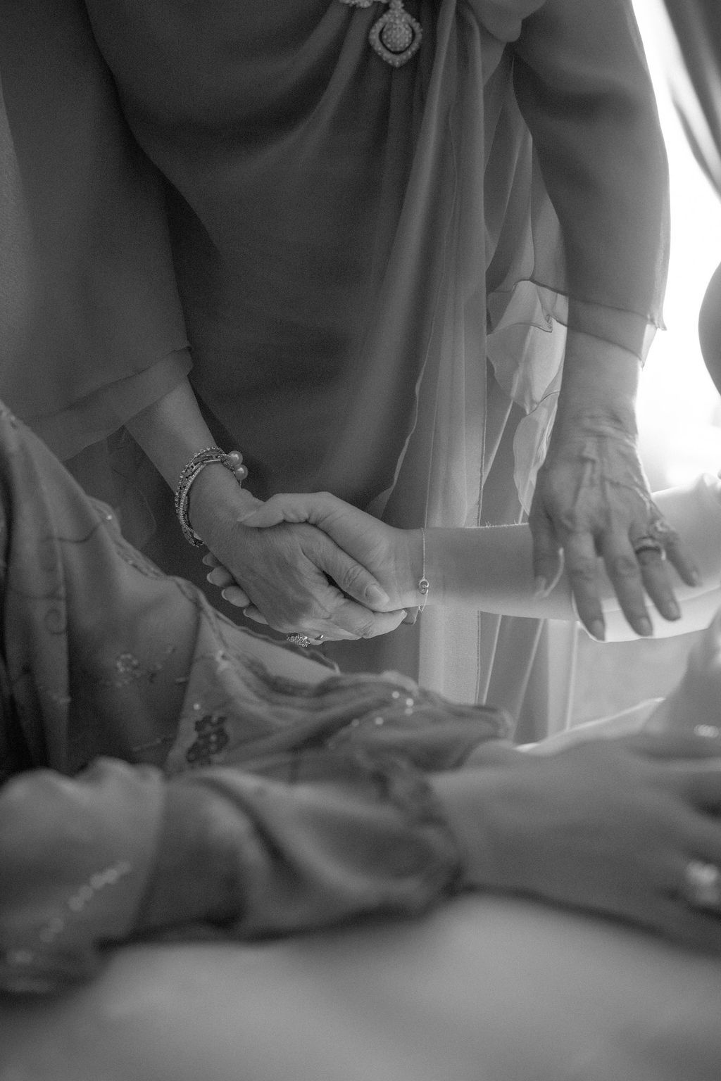 Close-up black and white shots of hands working with fabric or material on a table.