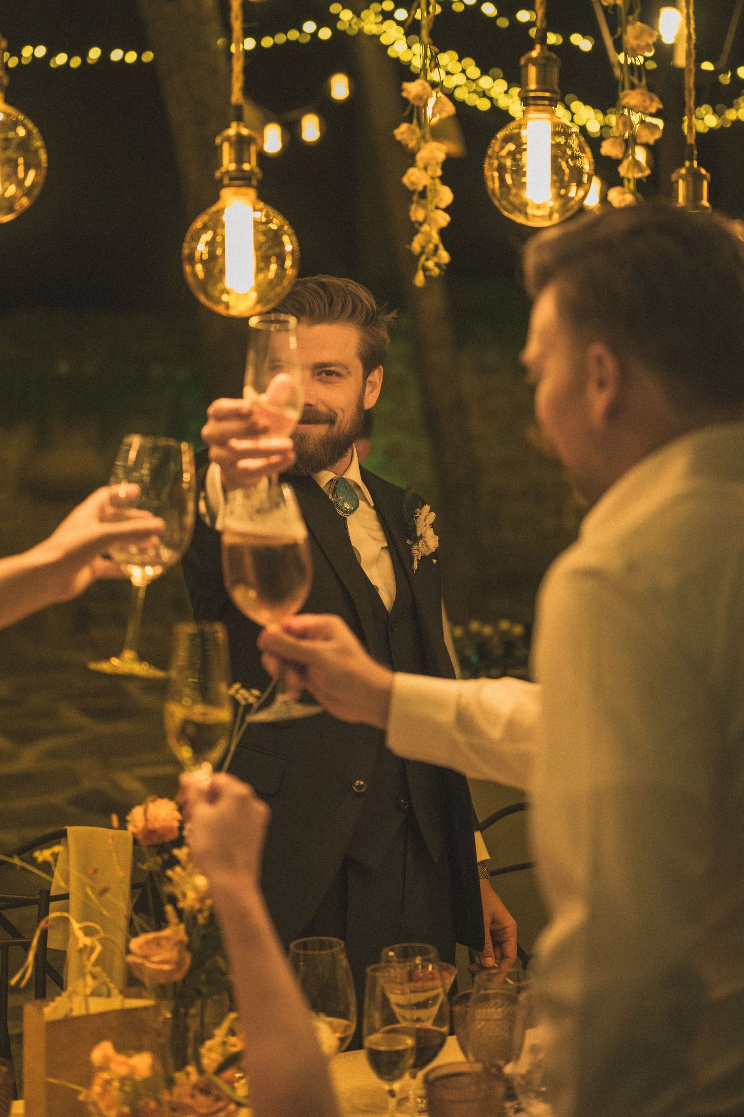 Guests enjoying drinks under warm string lights at an elegant evening reception.