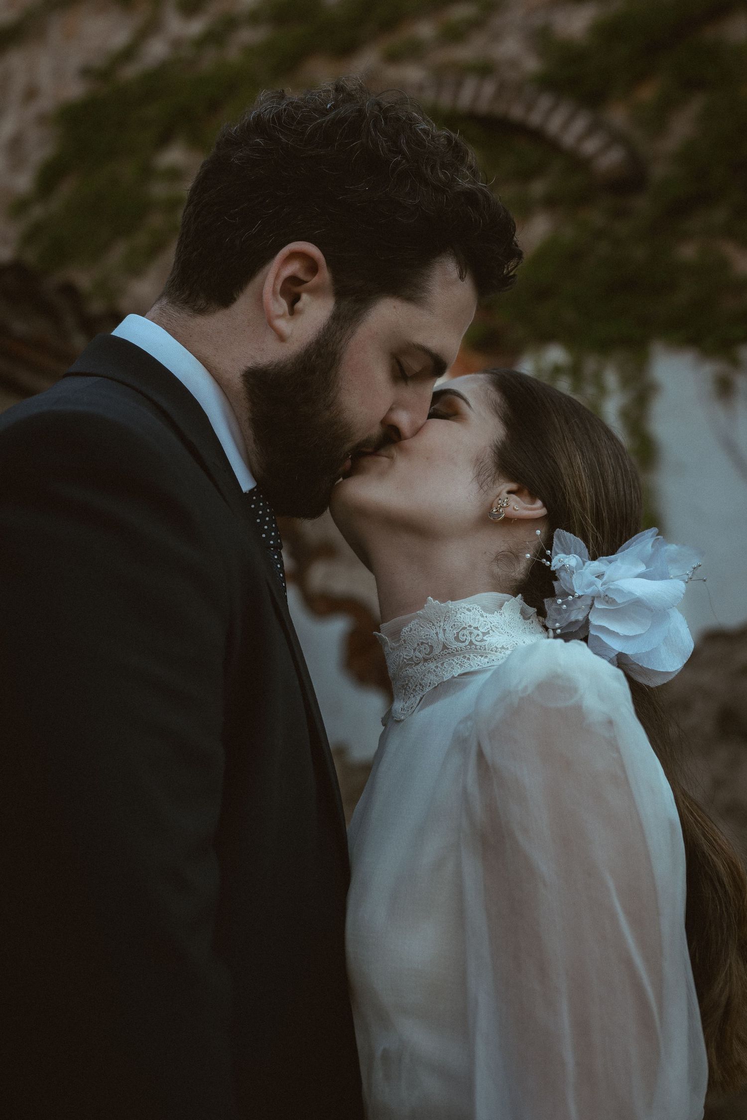A romantic twilight kiss between newlyweds in an outdoor setting.