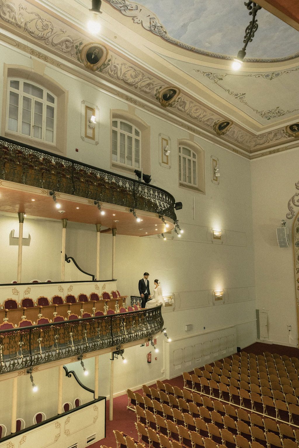 Historic theater auditorium with ornate ceiling details and rows of classic wooden seating.