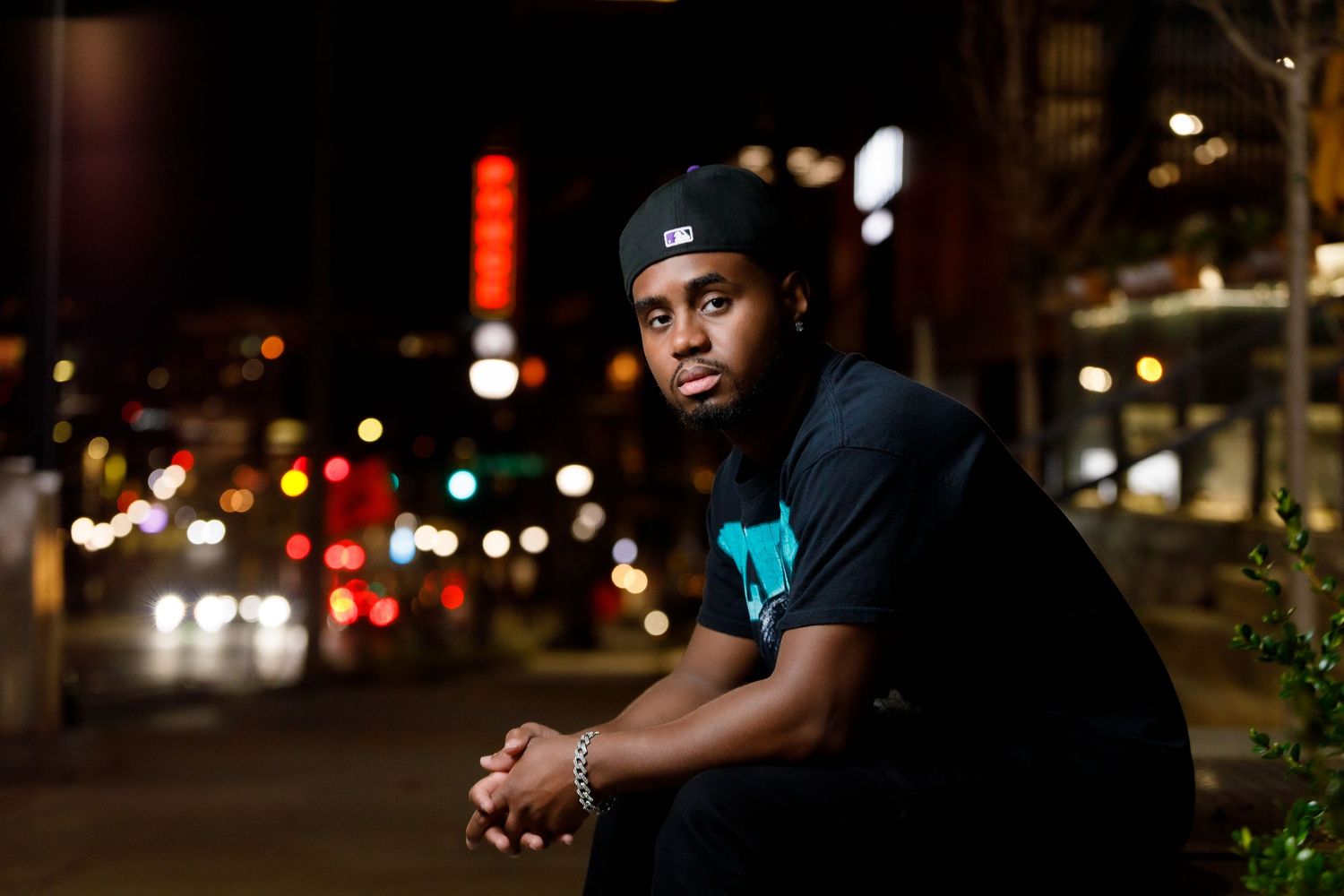Person sitting on urban steps at night with city lights glowing in the background.