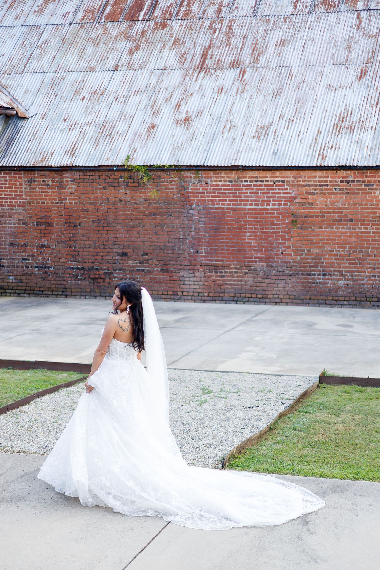 Elegant bridal portraits showcasing a flowing white wedding gown with cathedral train against brick walls.