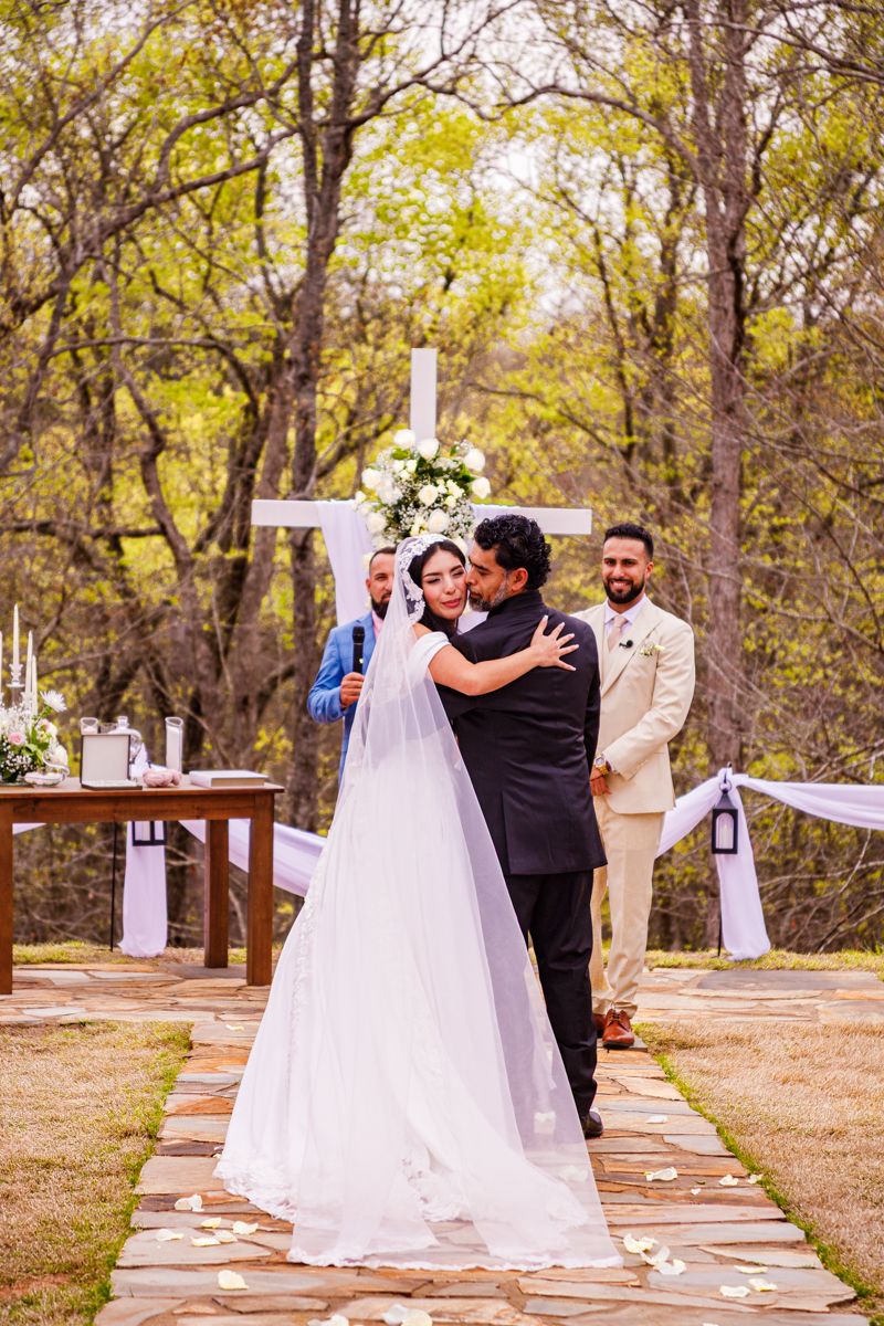 Wedding ceremony sequence showing a couple dancing in an outdoor wooded setting with white decor.