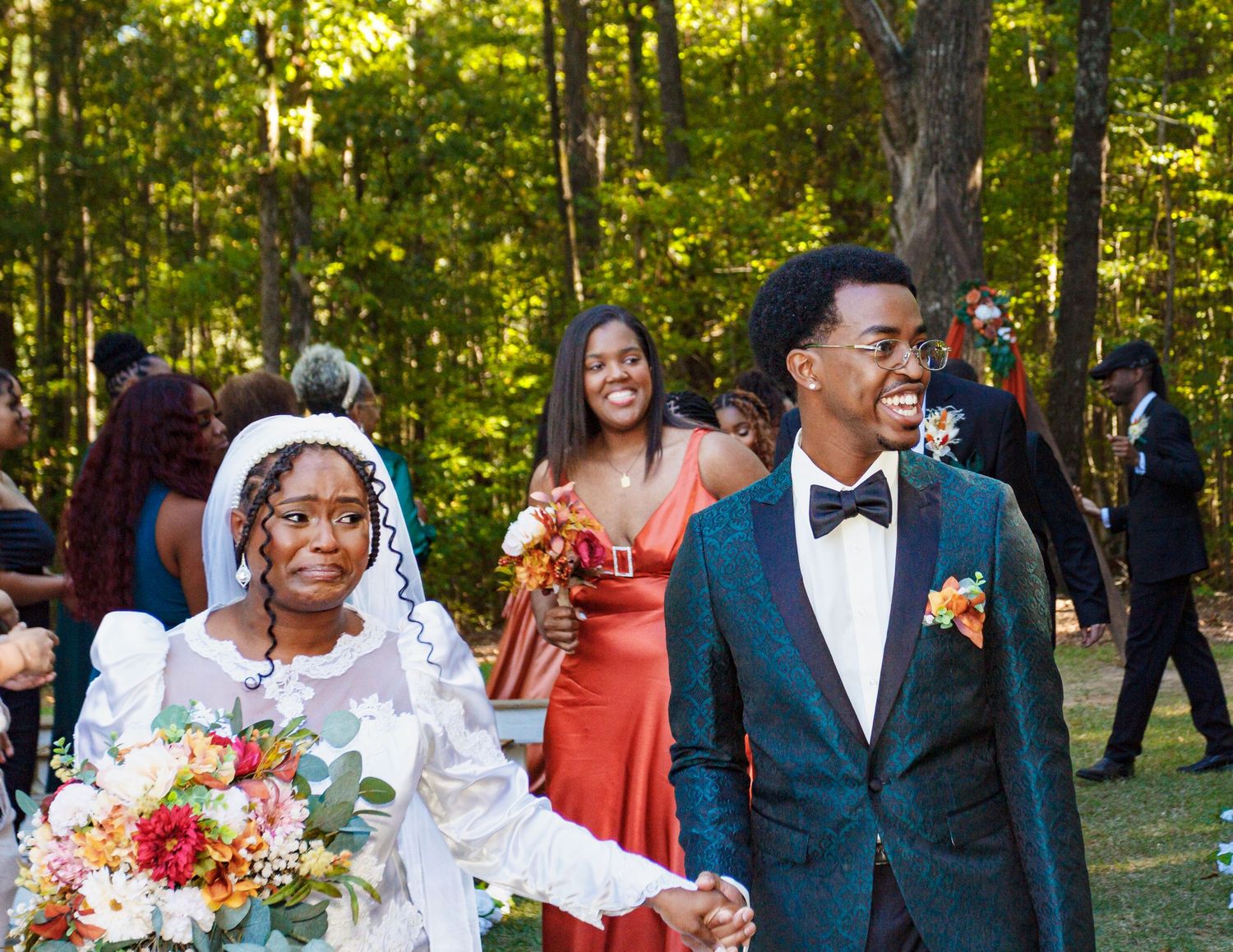Wedding party celebrates outdoors in formal attire with coral and navy color scheme.