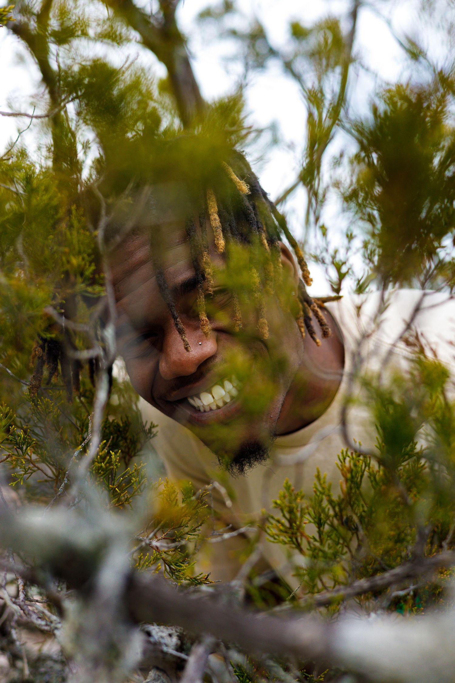 Artistic portrait series showing blurred faces through green foliage creating a dreamy natural effect.