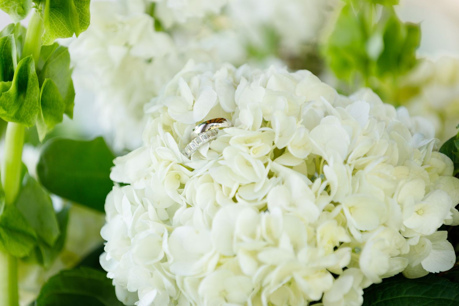 White carnation bouquet with wedding ring detail nestled among the petals.