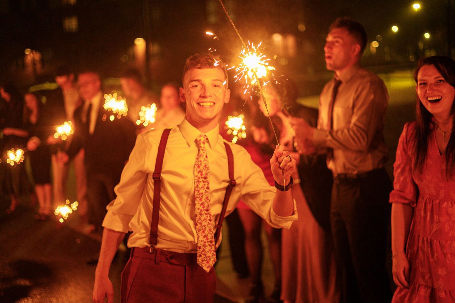 People celebrating at night with sparklers creating a festive atmosphere in warm glowing light.