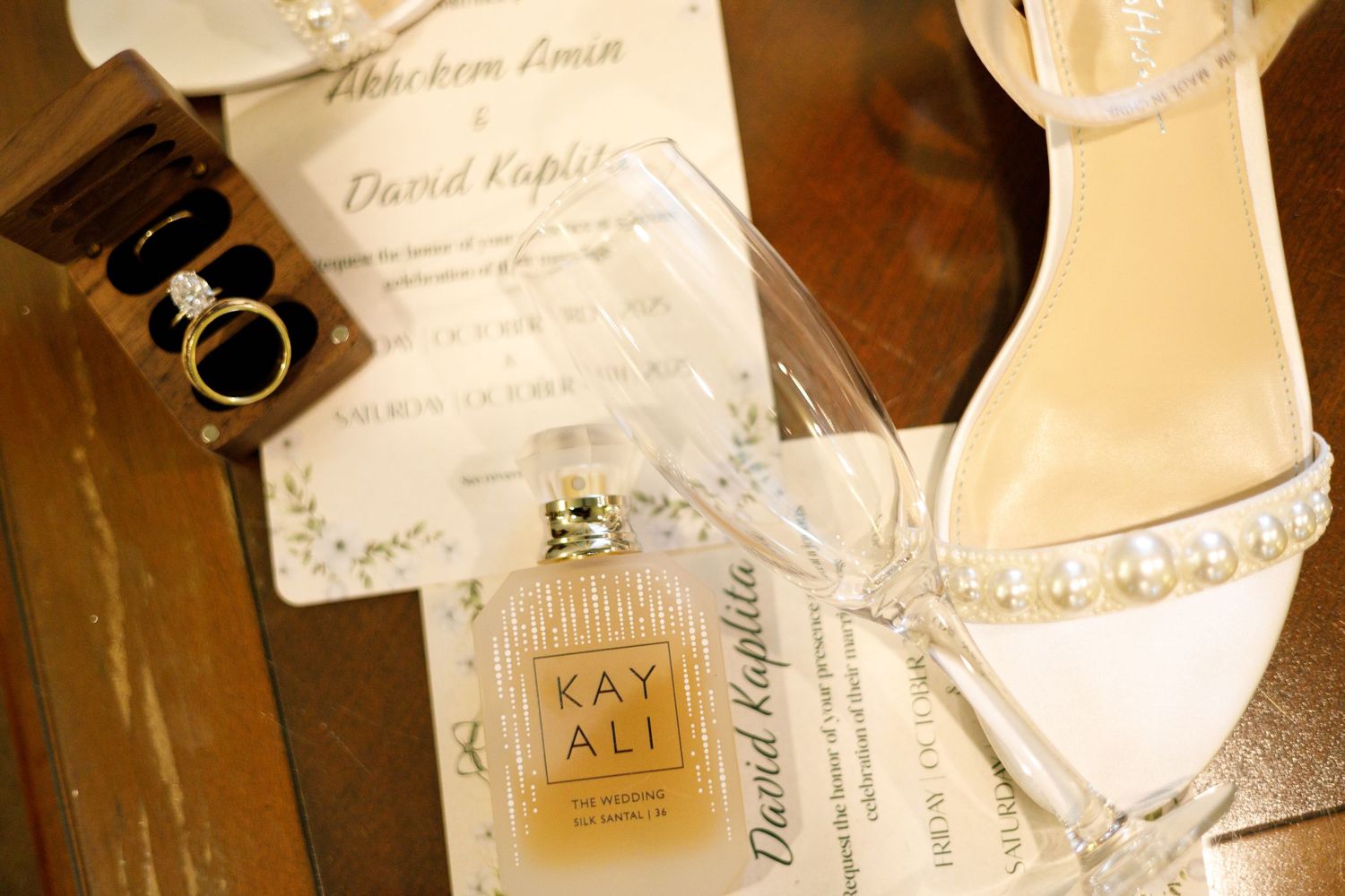 Wedding details including invitation, perfume bottle, and pearl-adorned bridal shoes.