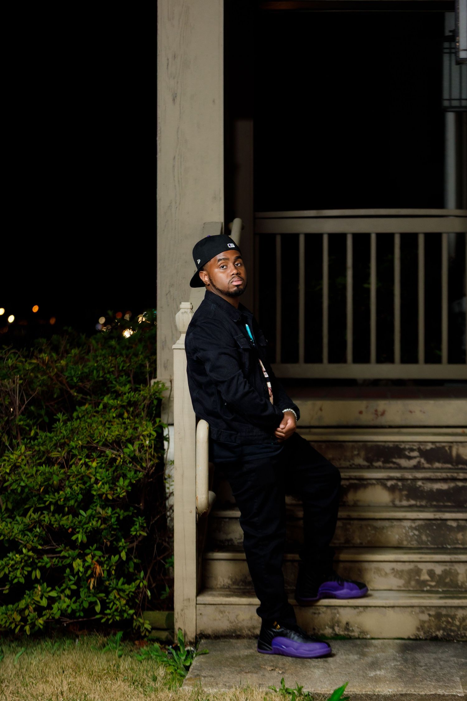 A person in dark clothing sits on concrete steps outside a building with a purple object nearby in a sequence of photos.