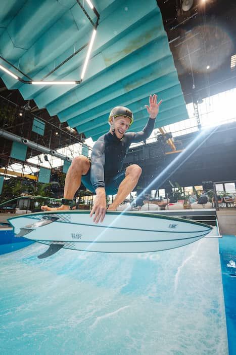 Surfer beim Indoorsurfen im Rheinriff, direkt im Sprung ein Lichtstrahl unterstreicht die Aktionsszene