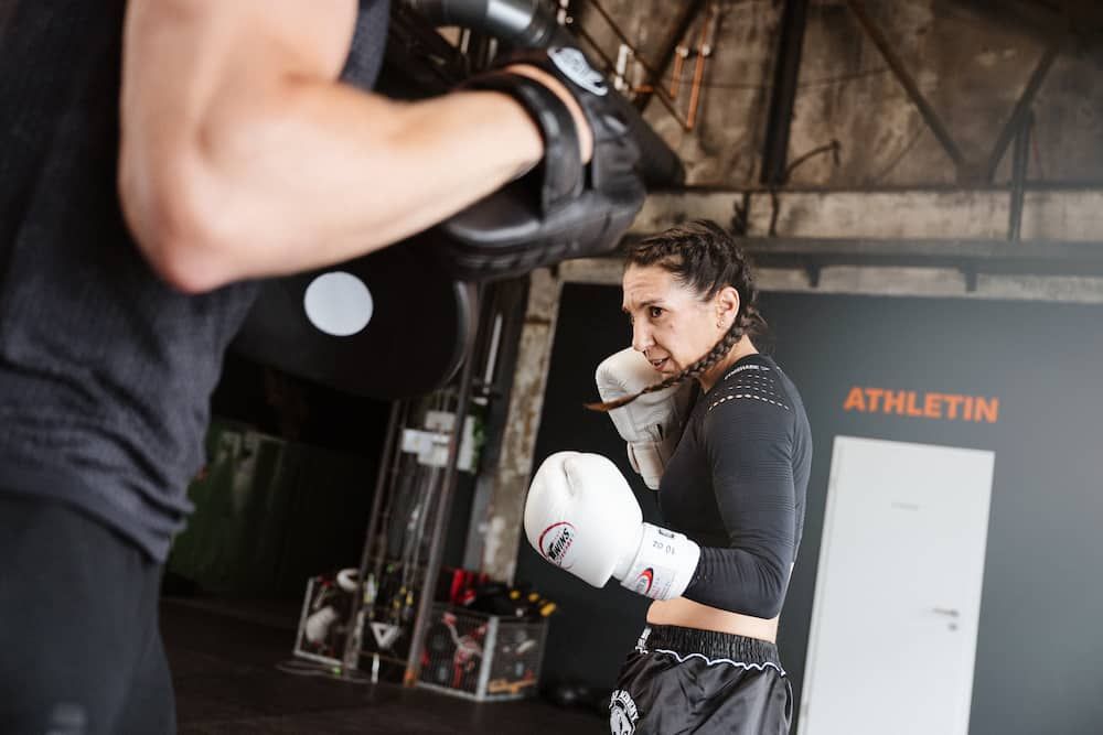 Kämpferin Biggi Baum beim Sparring mit ihrem Partner. Sie hat die Handschuhe am Gesicht, bereit für den Schlag.