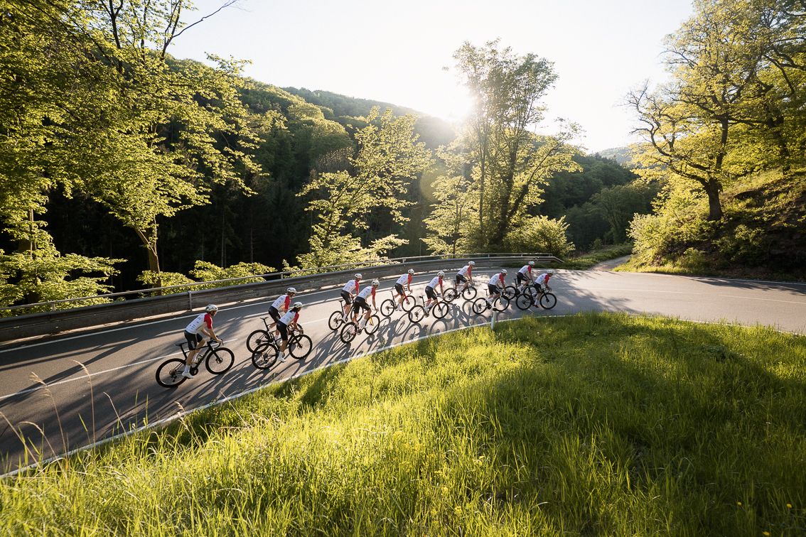 Gruppenfoto des 2RC Format Radrennteam in Action wie sie den Berg hochfahren. Die Sonne scheint.