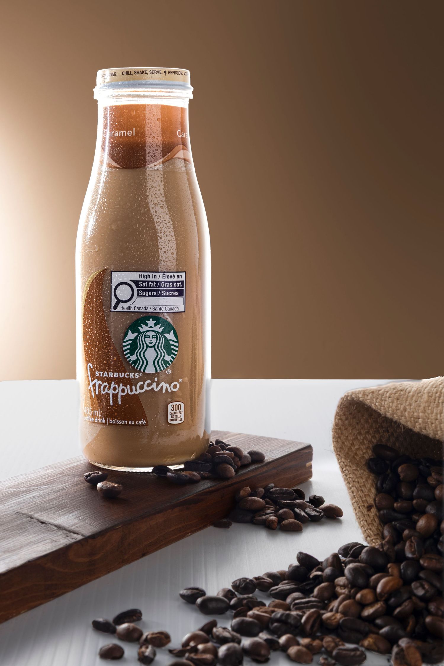 Starbucks Caramel Frappuccino with a brown background and bag of coffee beans