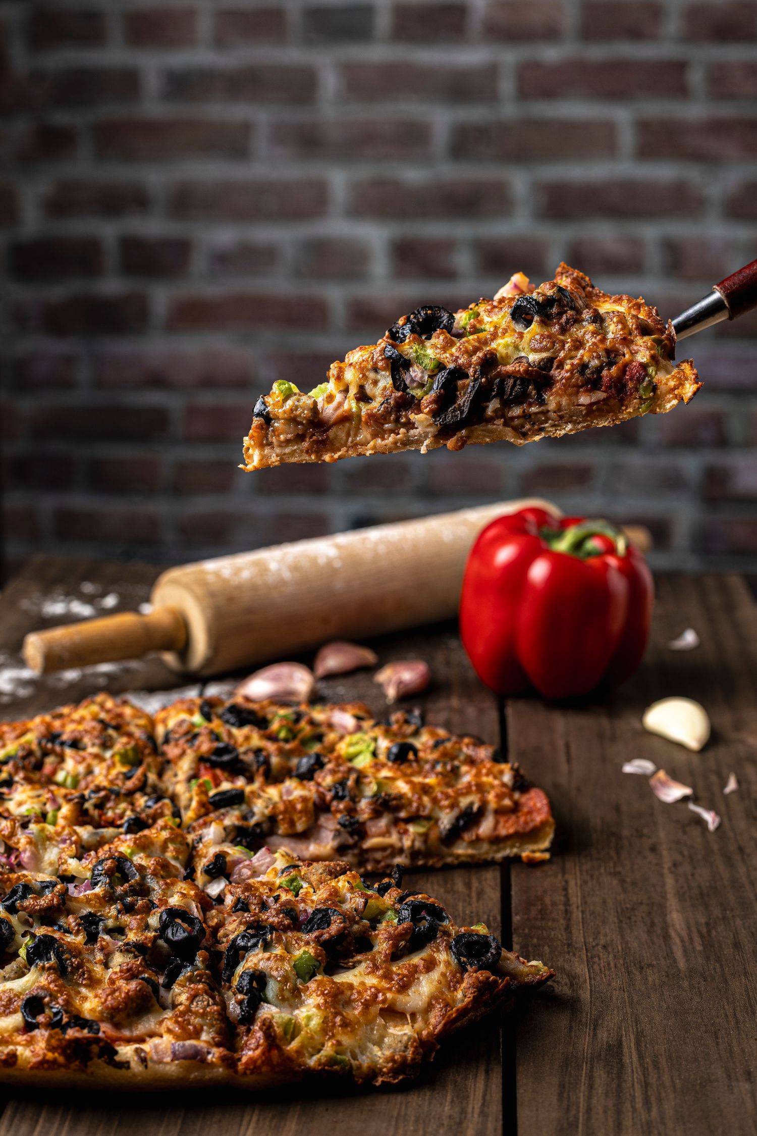 Dramatic shot of fully loaded pizza slice being pulled