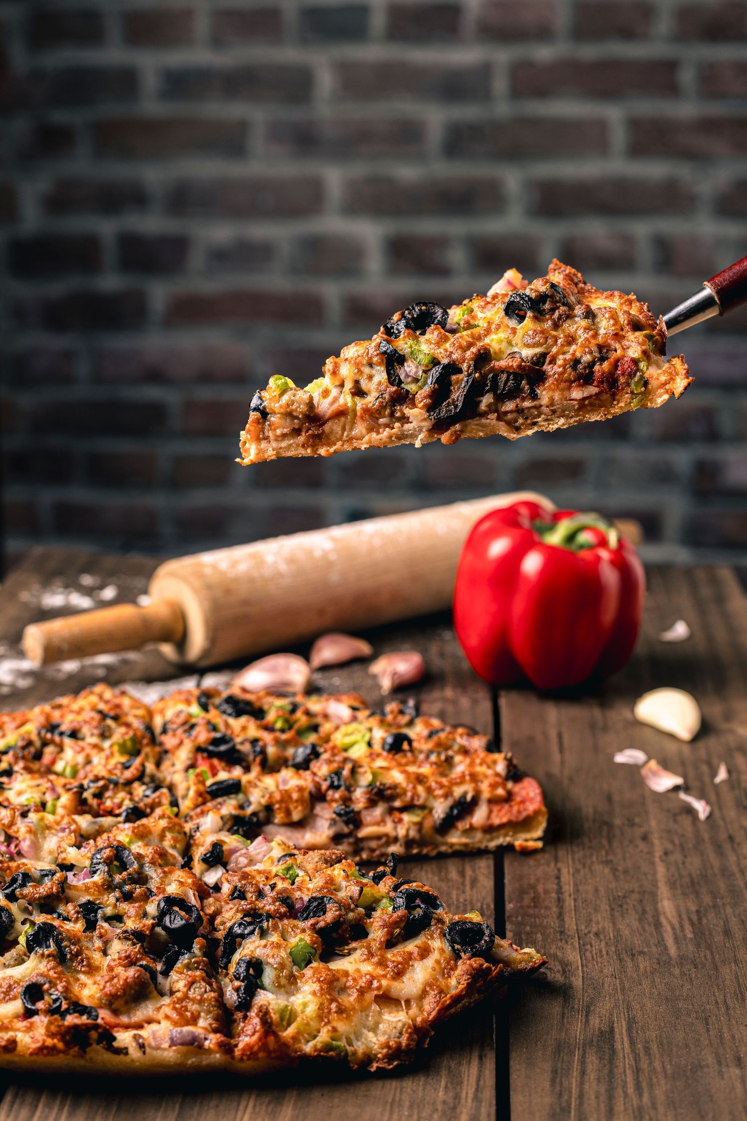 Dramatic shot of fully loaded pizza slice being pulled