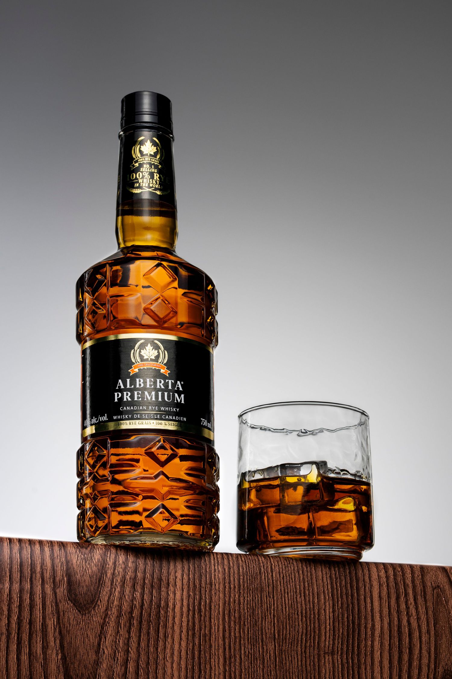 Alberta Premium bottle and whisky on the rocks on wooden surface, elegant product photography