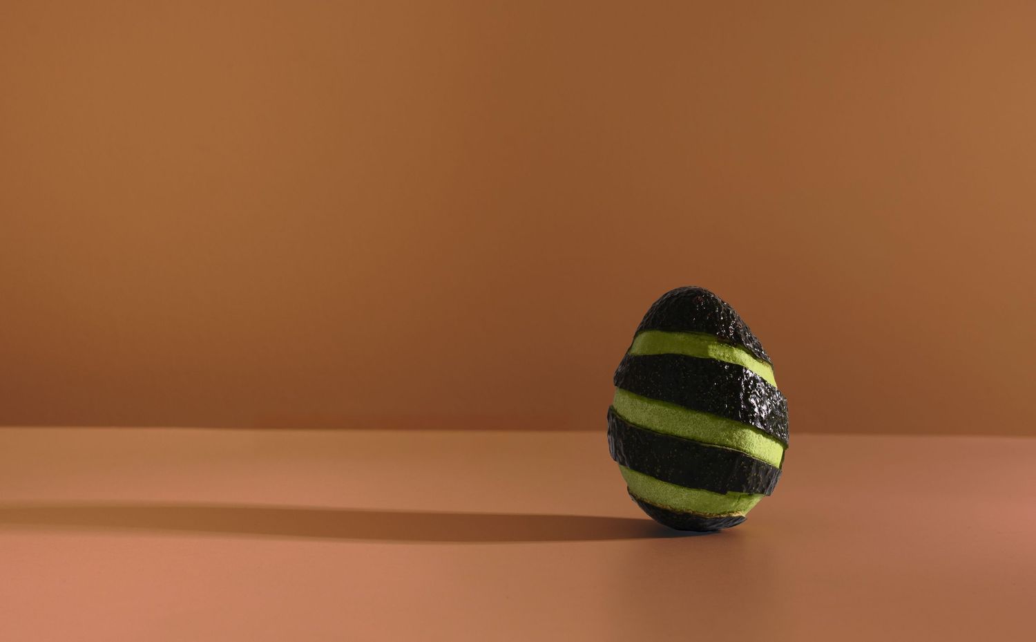 Spiral cut avocado on a brown background