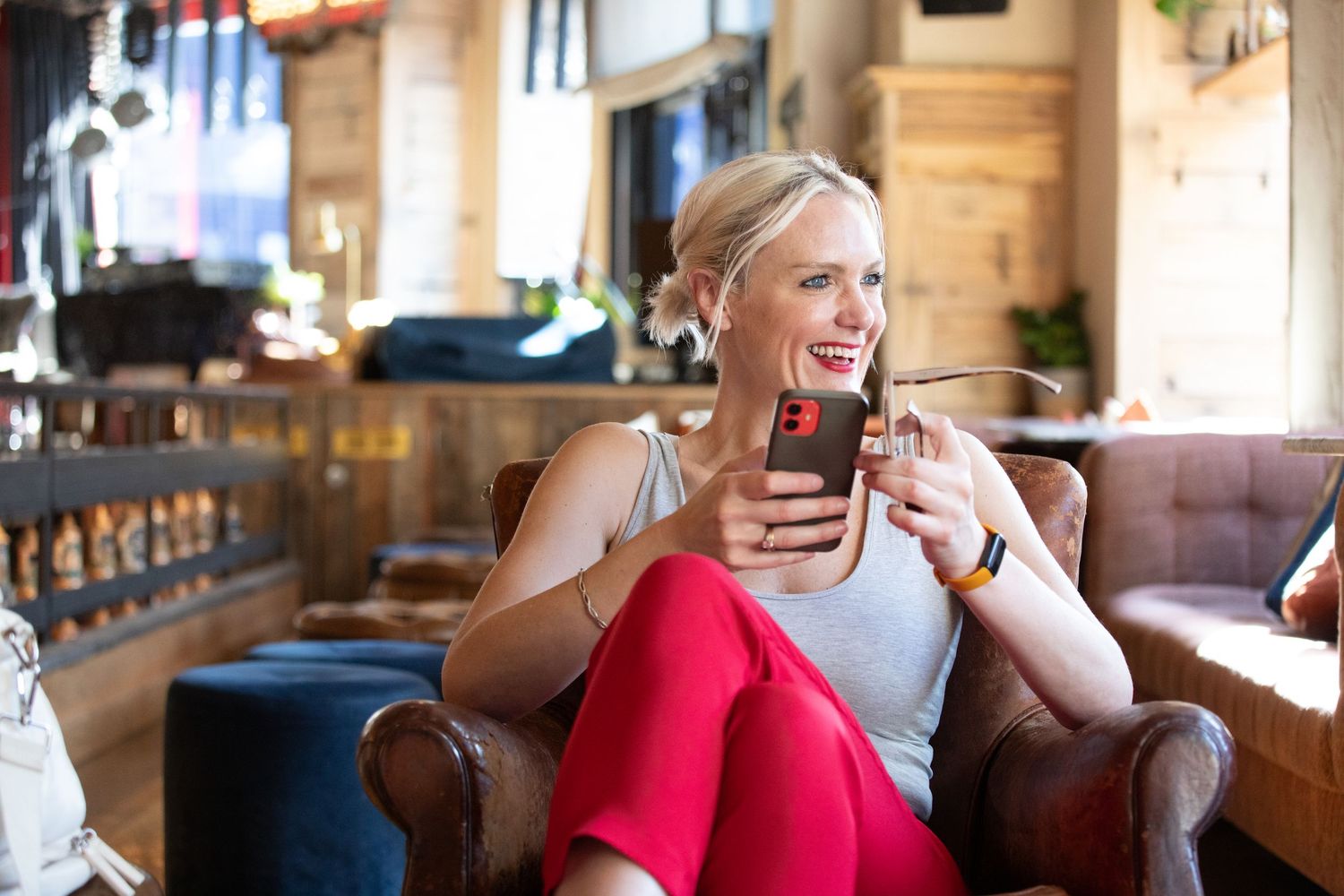 Person smiling while lounging on brown leather furniture in a bright room.