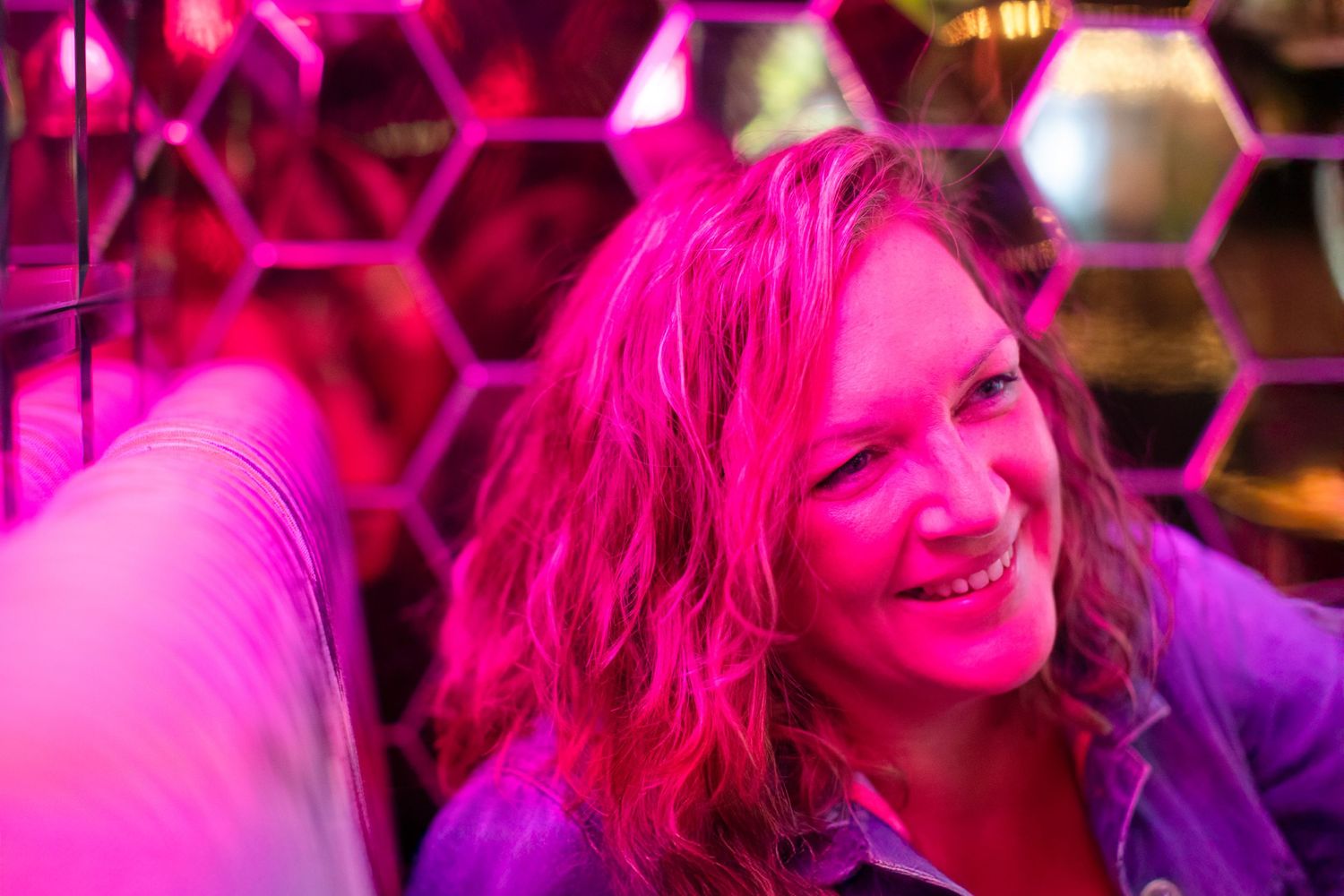 Close-up portrait under intense pink lighting with dynamic shadows and highlights.