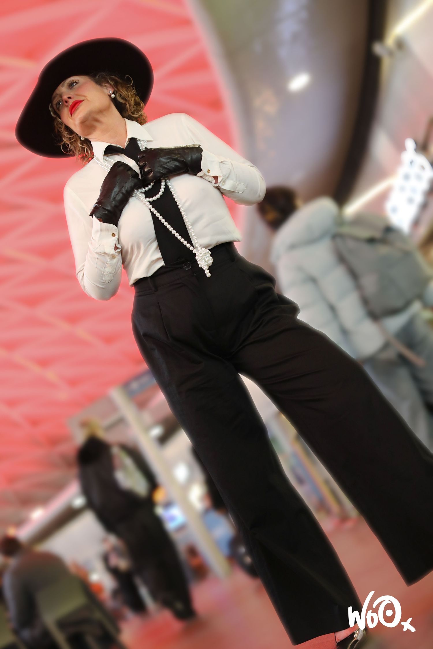 Performer in vintage black and white costume with hat poses dramatically on stage.