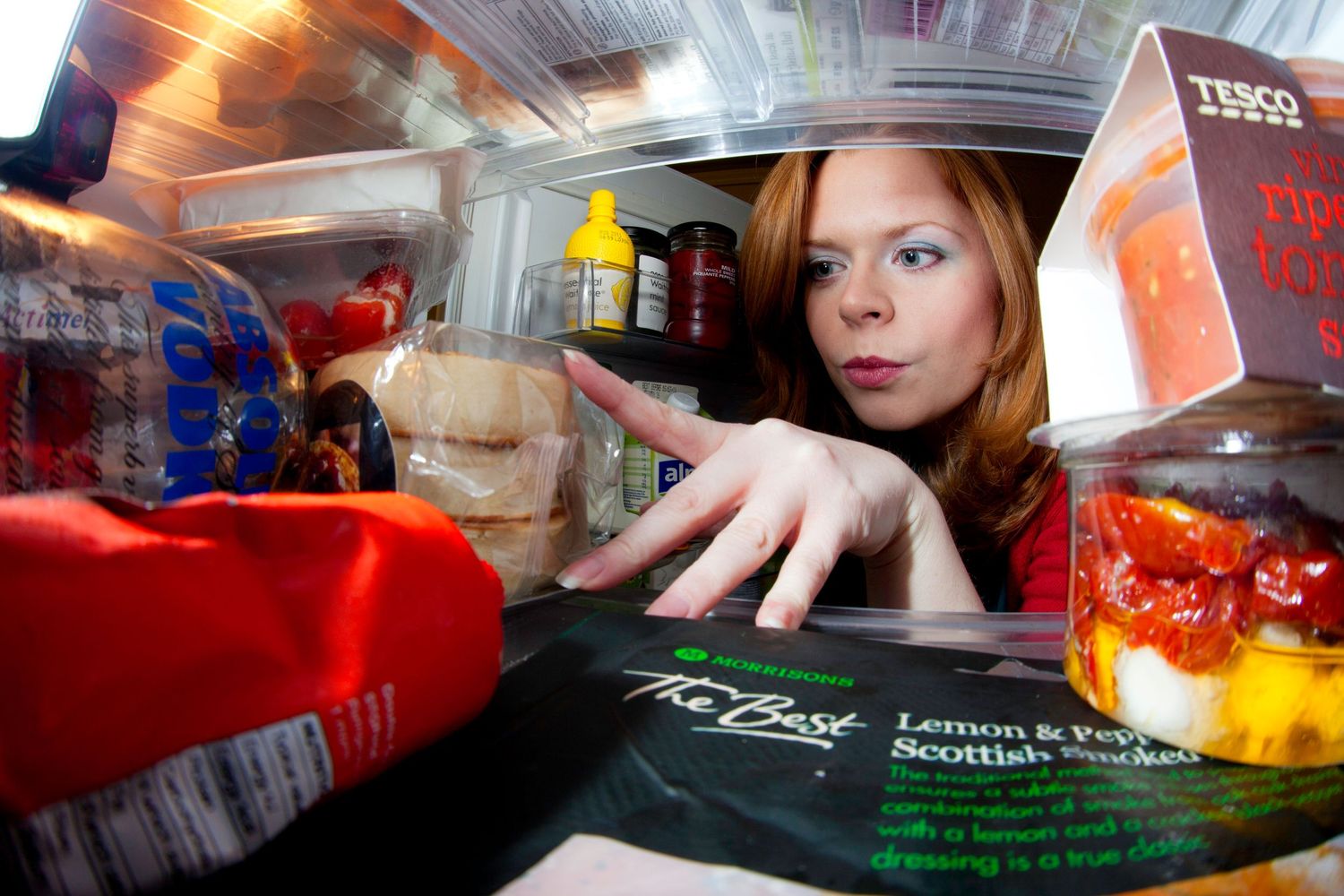 Looking into colorfully lit refrigerator interior with various items on shelves.