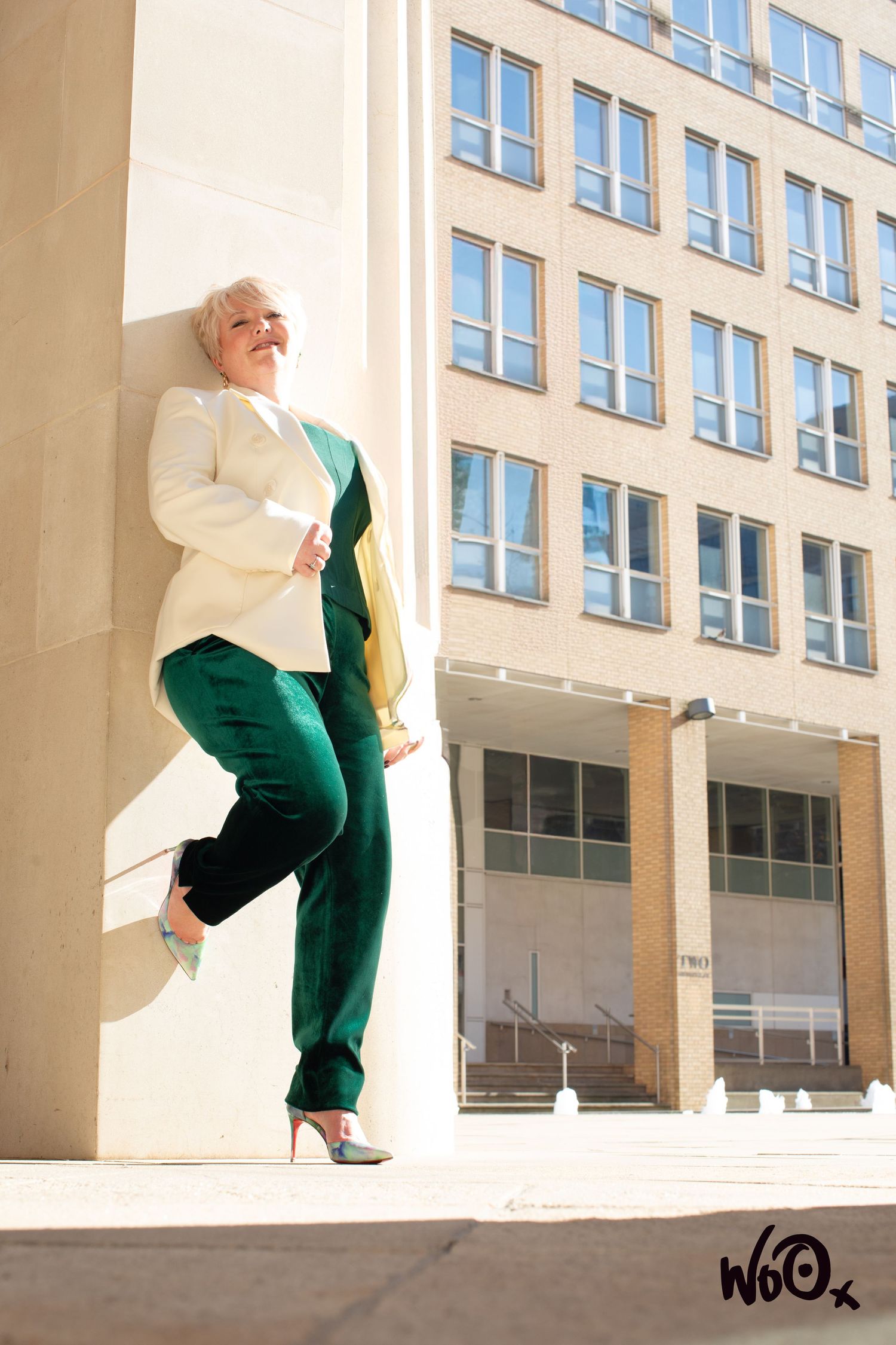 Modern architectural fashion shoot with flowing white and green garments against urban building.