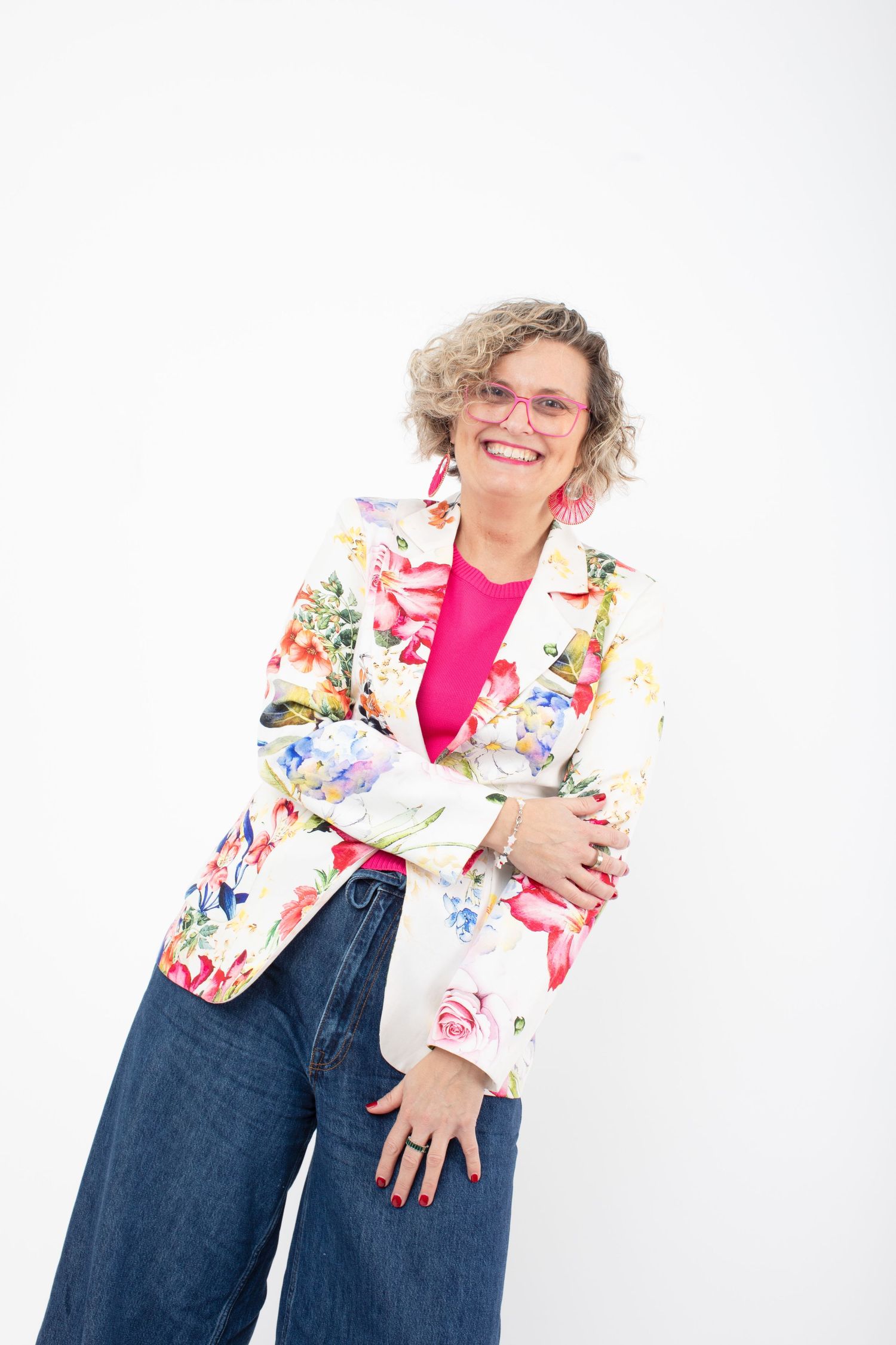 Person wearing colorful floral blazer and pink shirt with wide-leg jeans against white background.