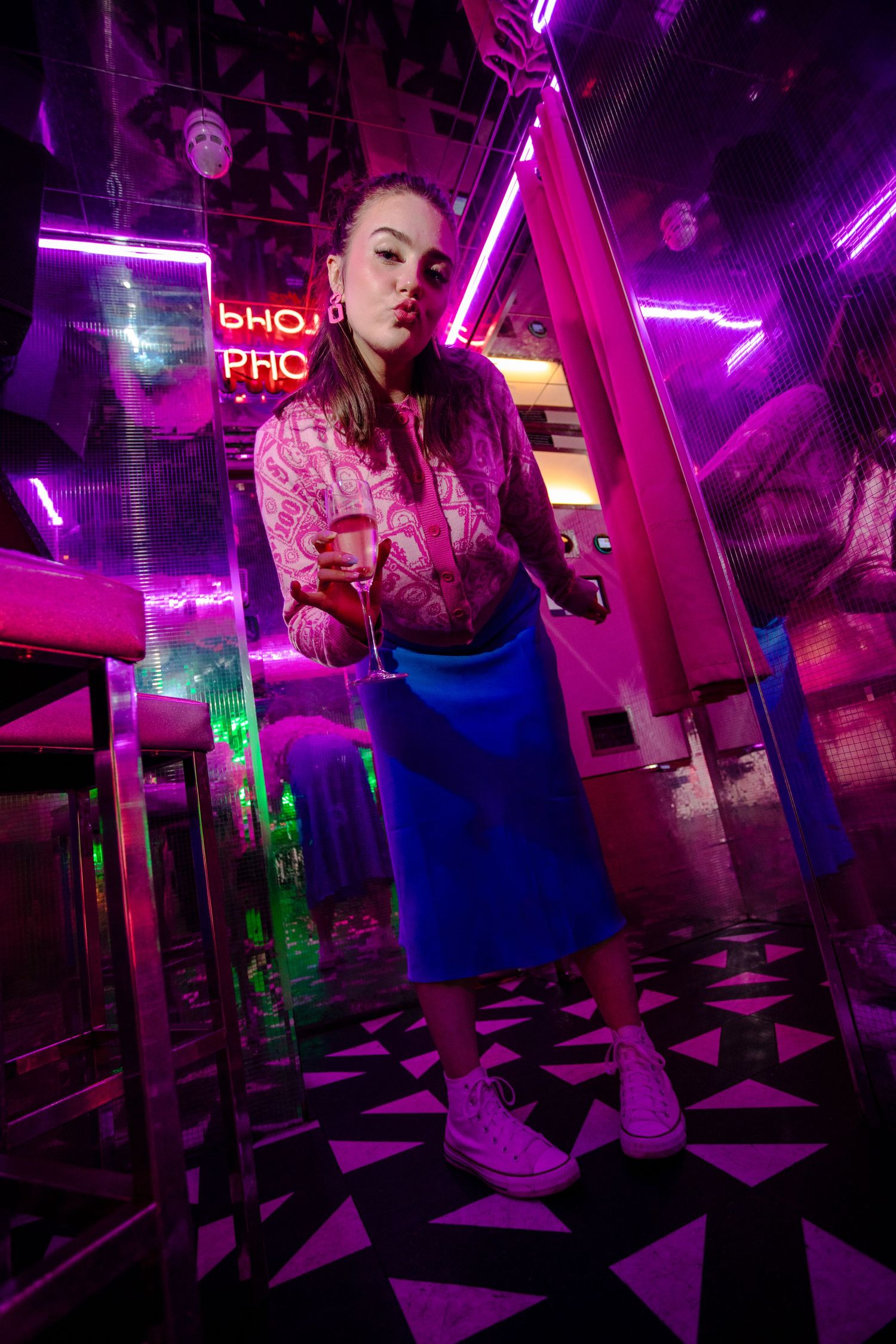 Moody nightclub portrait with vibrant neon lighting and geometric floor pattern.