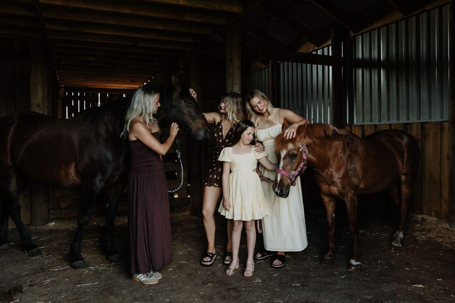 Dark silhouettes of people and horses gather inside a dimly lit barn setting.