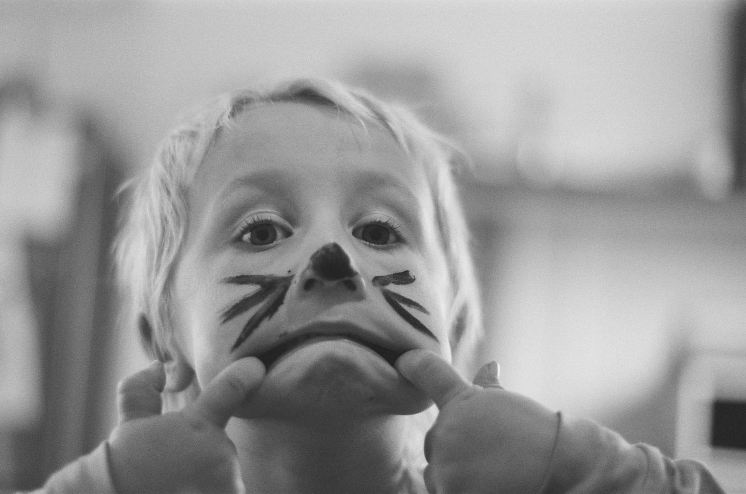 Black and white portrait with face paint whiskers.