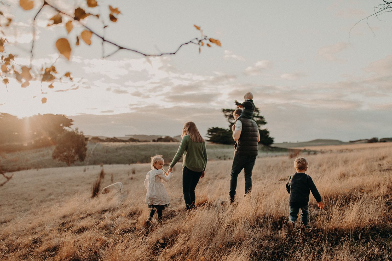 Silhouettes of family walking along hilltop path during golden sunset.