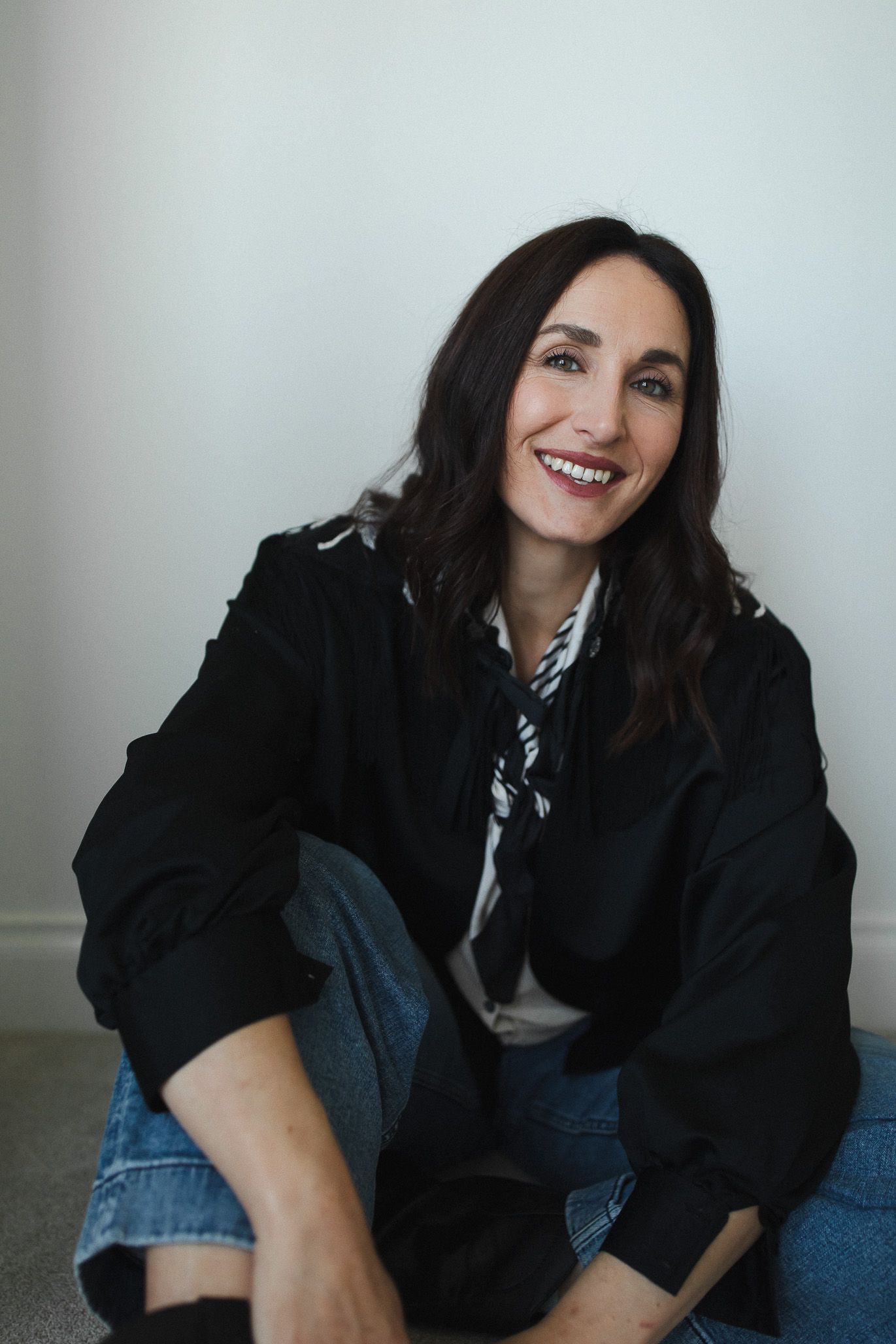 A series of candid portrait shots showing a person in a black jacket and jeans against a light background.
