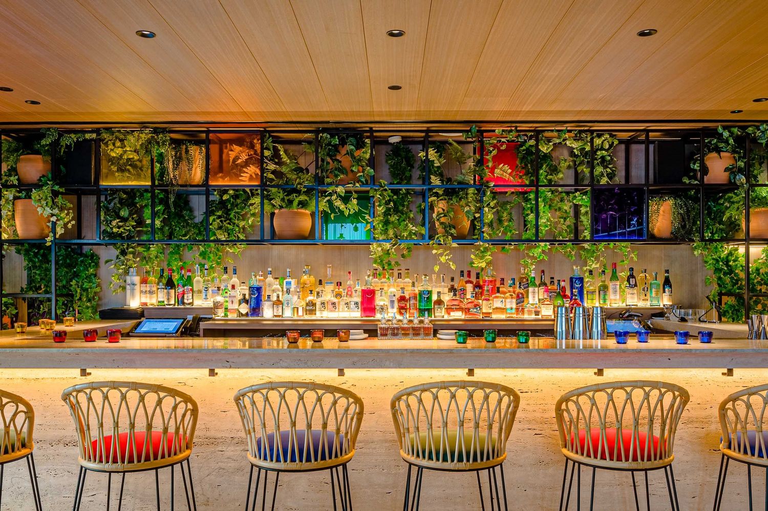 Detalle de interiorismo: exclusiva barra de bar con plantas y estanterías de vidrieras en The Madrid Edition.