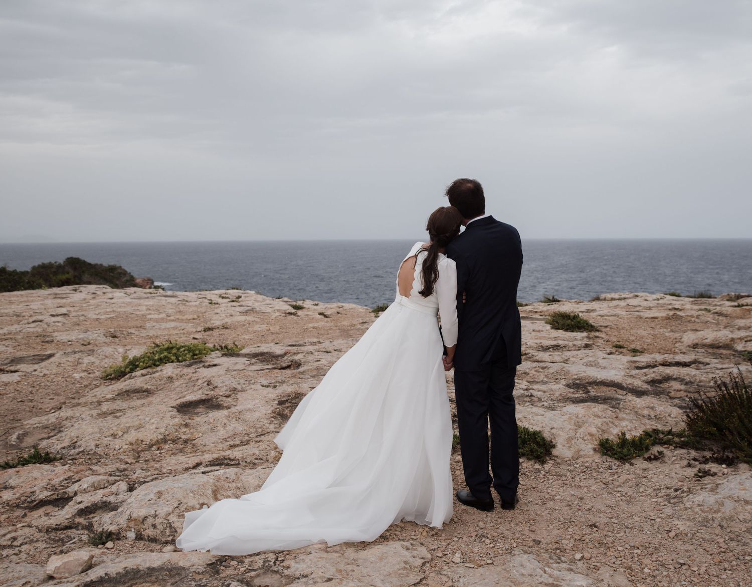 NOVIOS DESPUES DE LA CEREMONIA MIRANDO AL MAR ABRAZADOS