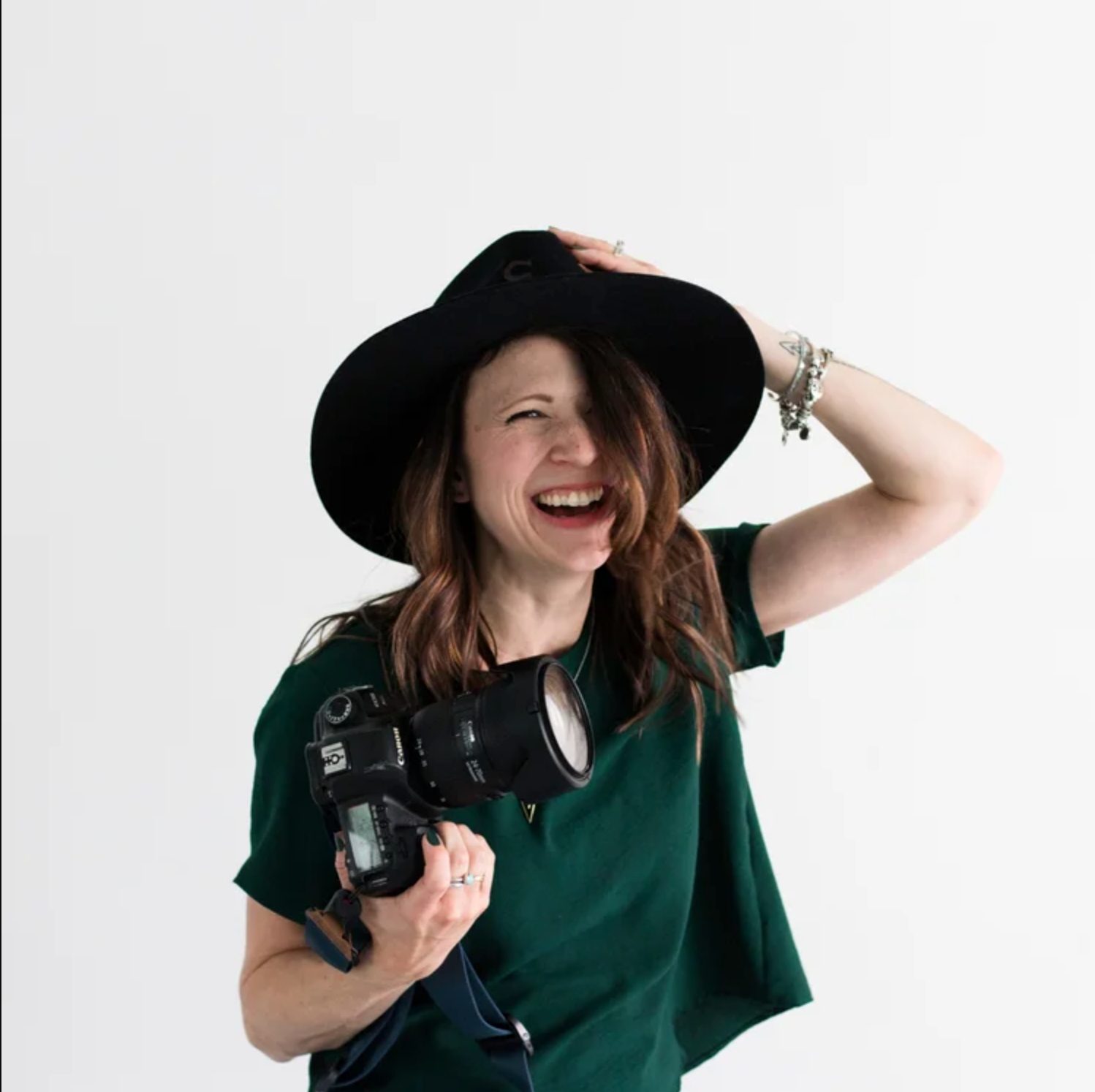 Woman in a green top and black hat holding a camera. Headshot photography Richmond, VA. Headshot photography RVA. Branding photography RVA.