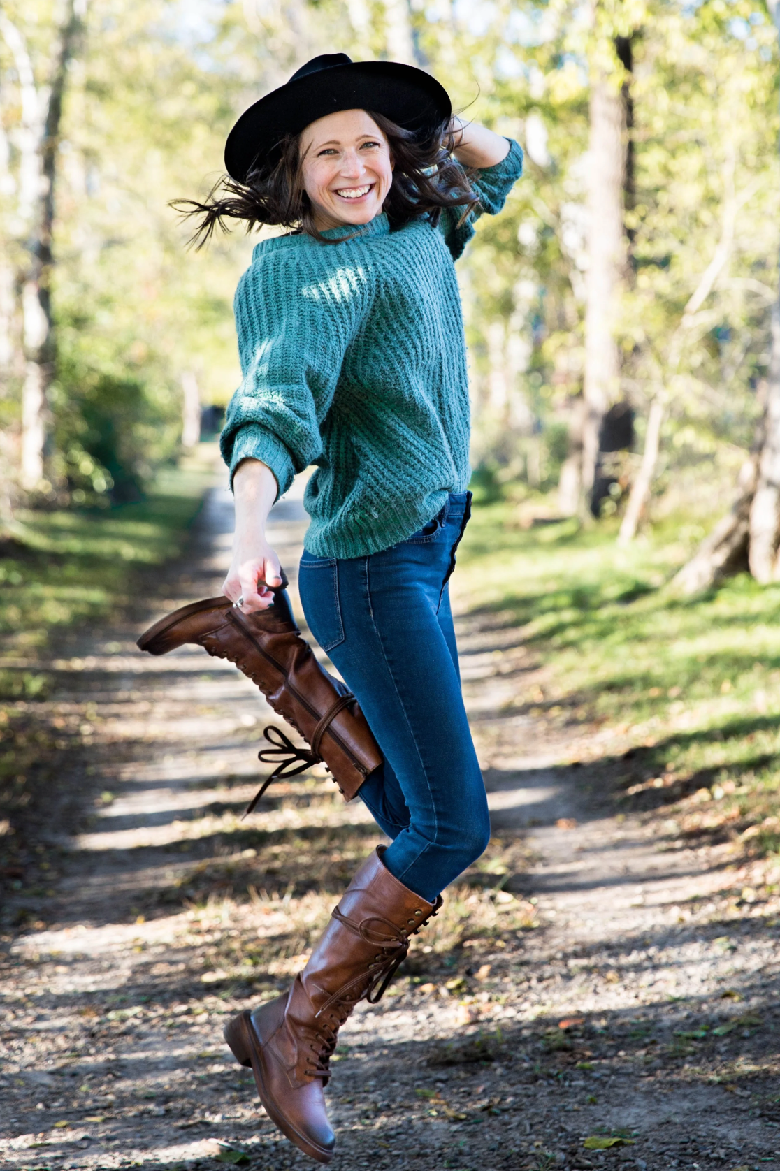 Woman in green sweater and black hat jumping up in joy. Woman in a green top and black hat holding a camera. Headshot photography Richmond.