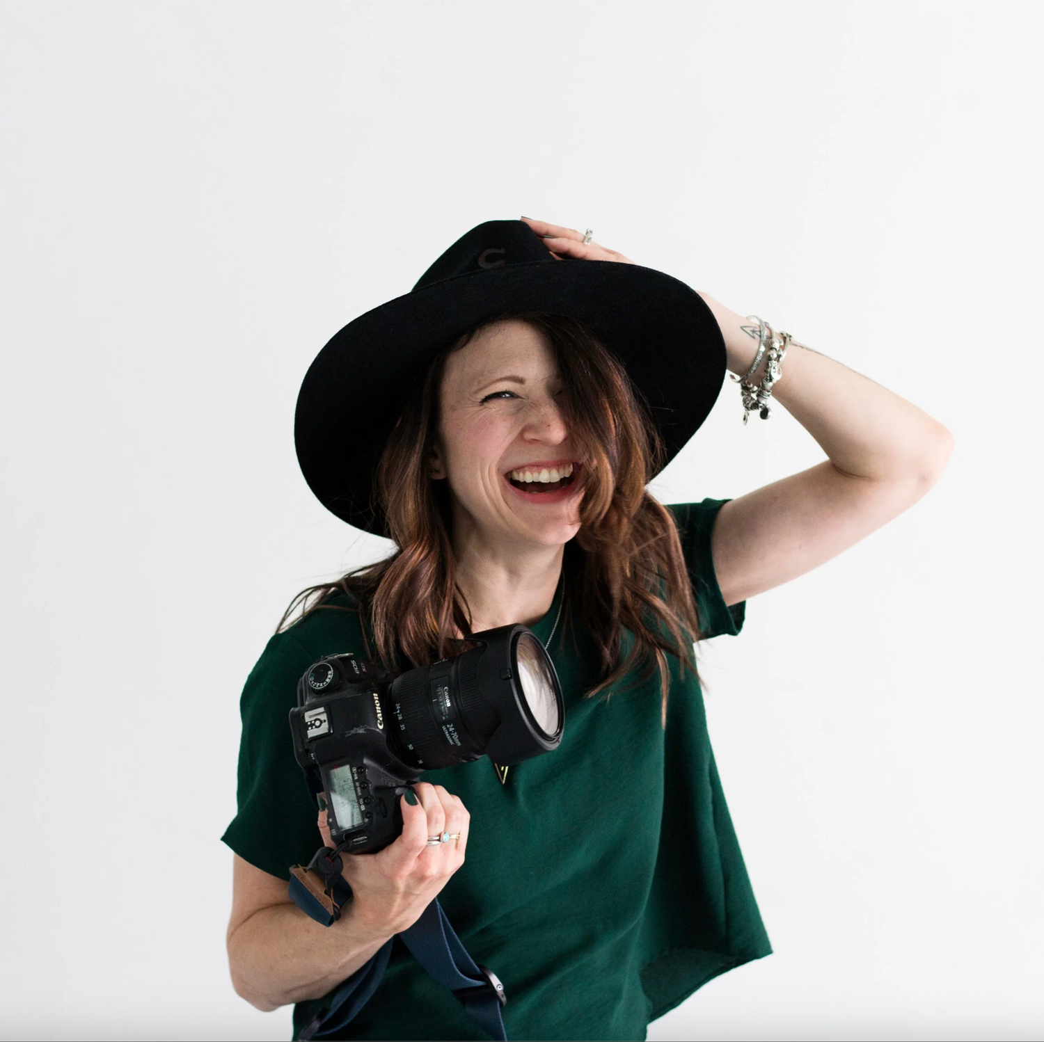 Woman in a green top and black hat holding a camera. Headshot photography Richmond, VA. Headshot photography RVA. Branding photography RVA.