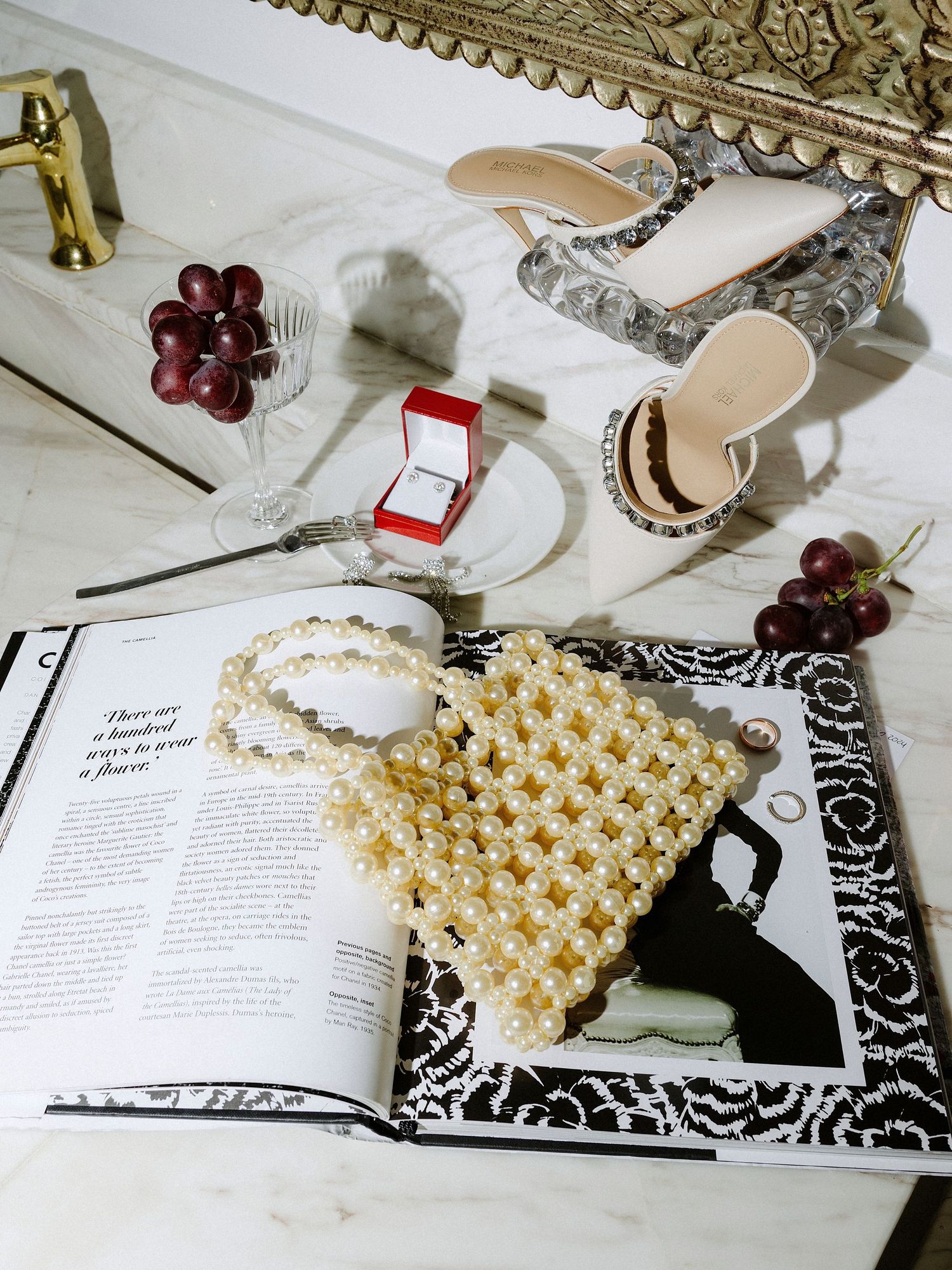 Wedding accessories including rings, pearls, shoes and jewelry arranged on an open book.